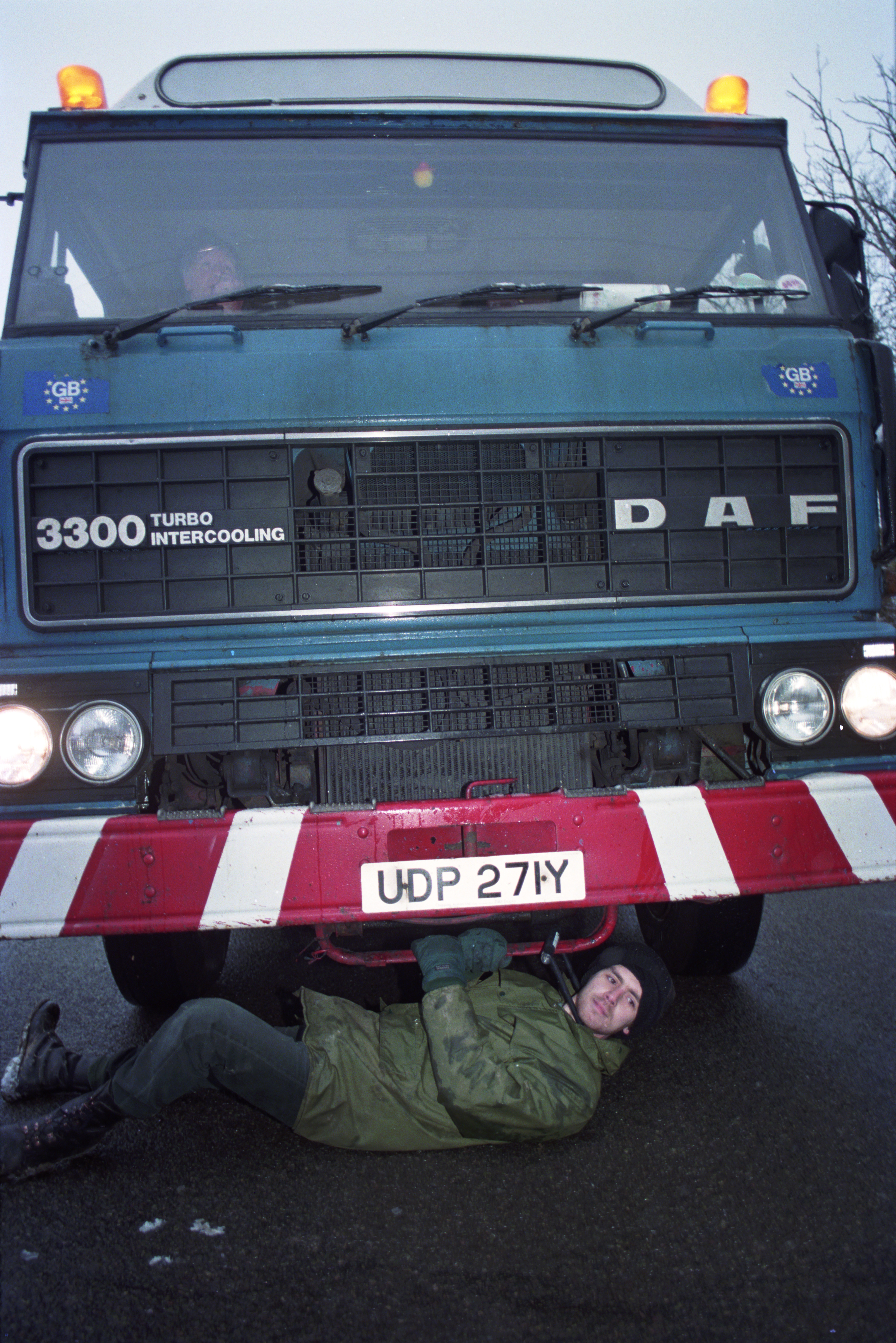 In a dawn raid, a man D-locks his neck to a convoy lorry carrying bulldozers