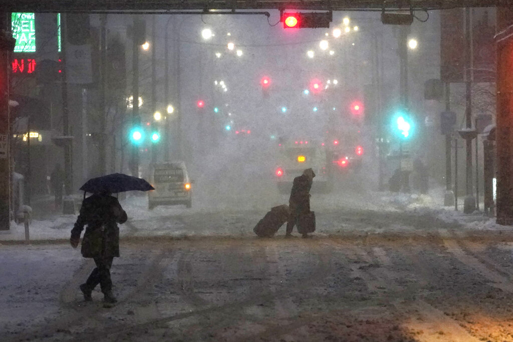 Pedestrians navigate Chicago's famed Loop in windy, falling snow and slushy street conditions.