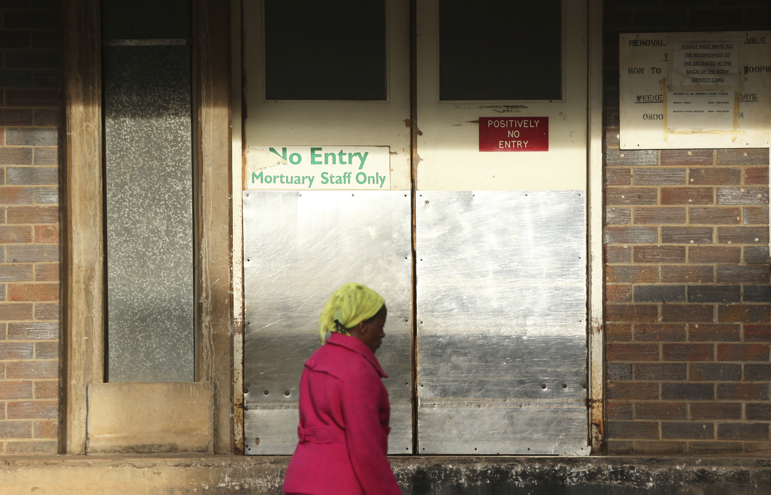 In this Jan. 9, 2019, photo, a woman walks past the mortuary entrance where a family collected the body of their son who died at Parirenyatwa Hospital in Harare, Zimbabwe. The family who blamed the death of their son on the doctors strike said they were devastated. A doctors strike in Zimbabwe has crippled a health system that was already in intensive care from neglect.It mirrors the state of affairs in a country that was full of promise a year ago with the departure of longtime leader Robert Mugabe but now faces economic collapse.