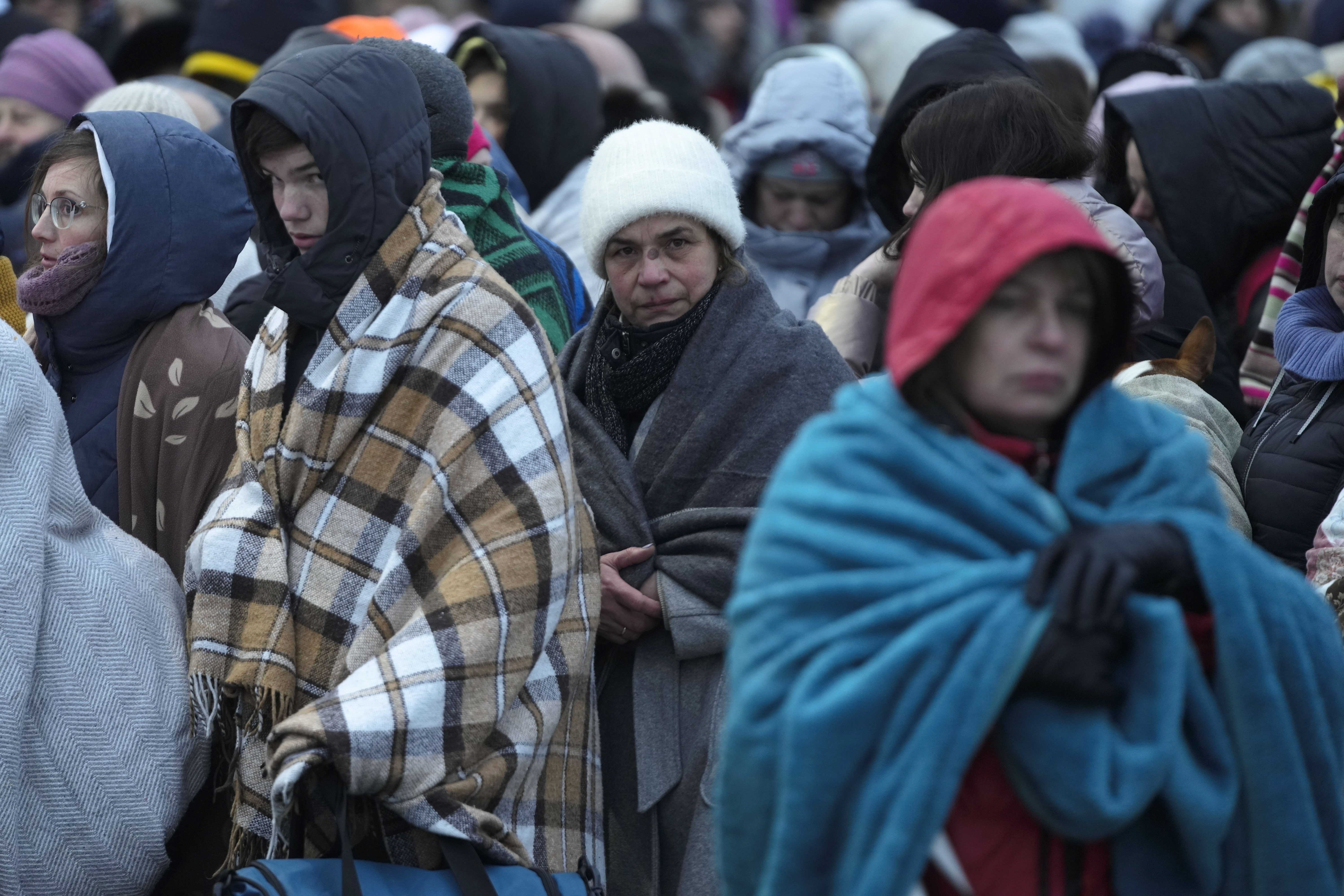 Refugees, mostly women and children, wait in a crowd for transport after fleeing from Ukraine and arriving at the border crossing in Medyka, Poland
