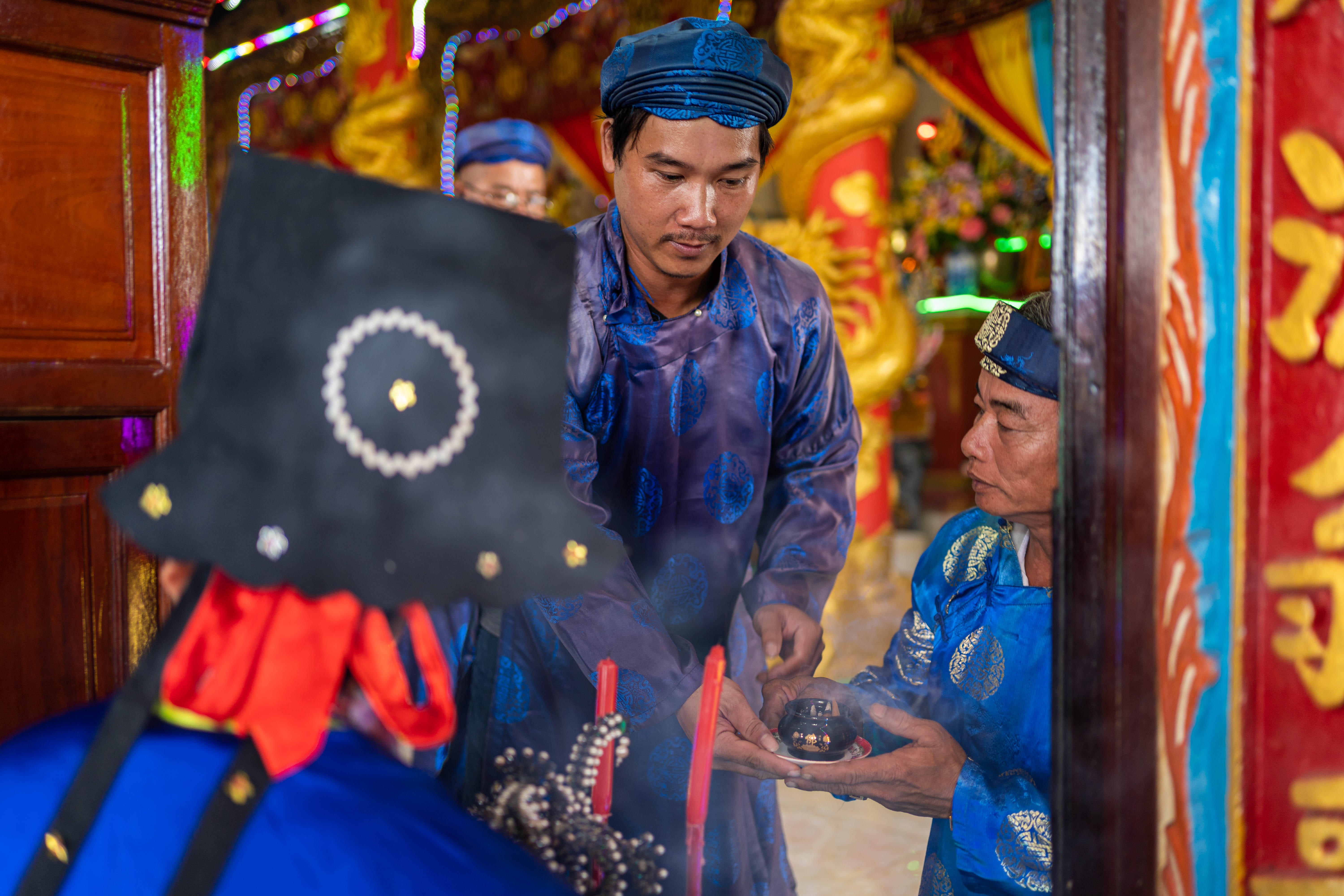 A photo of worshippers amid incense smoke and neon lights paying their respects to Cá Ông during Phuoc Hai’s whale worship festival.