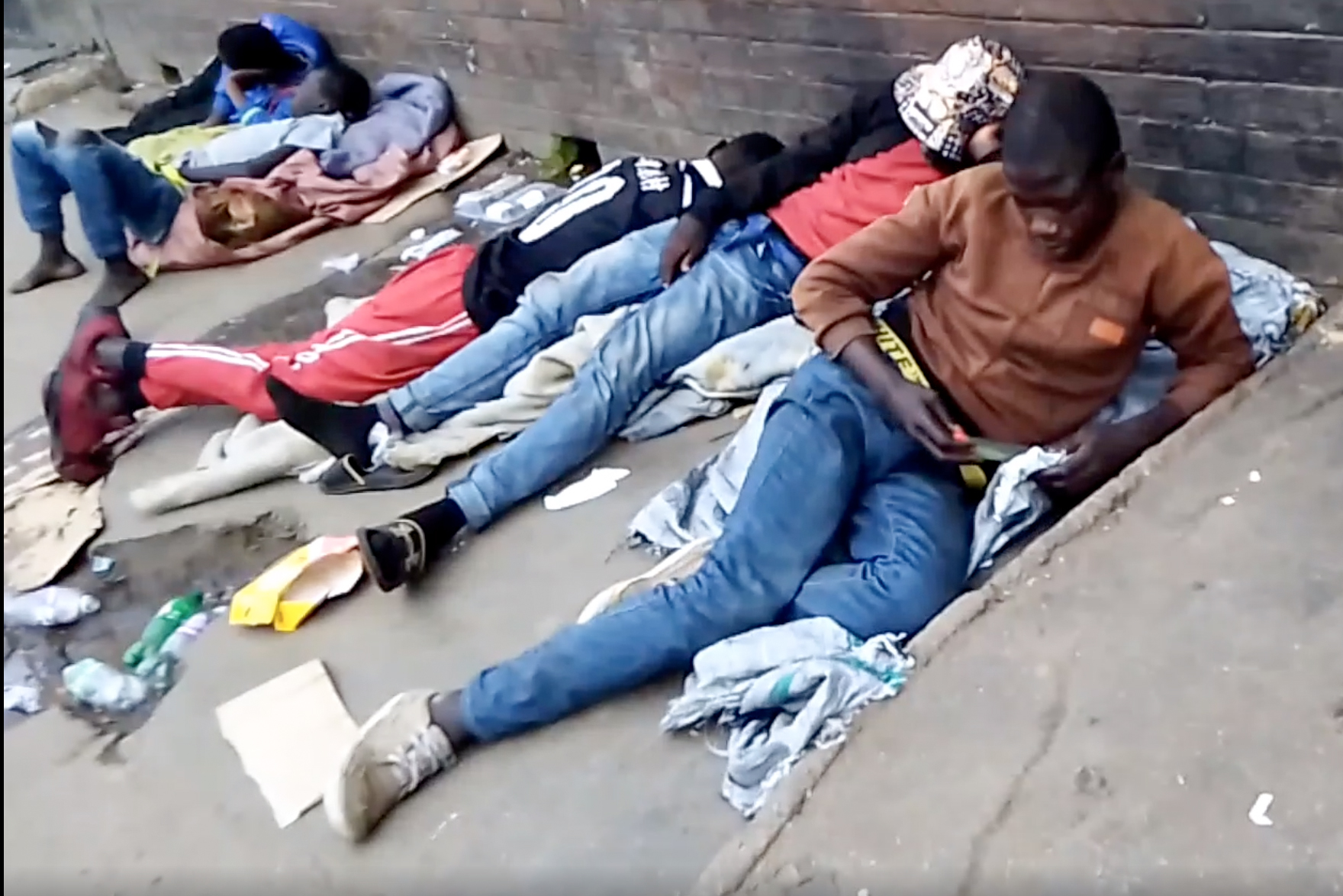 Youths lie down by the road in a suburb of Harare, capital of Zimbabwe, after inhaling sodium polyacrylate
