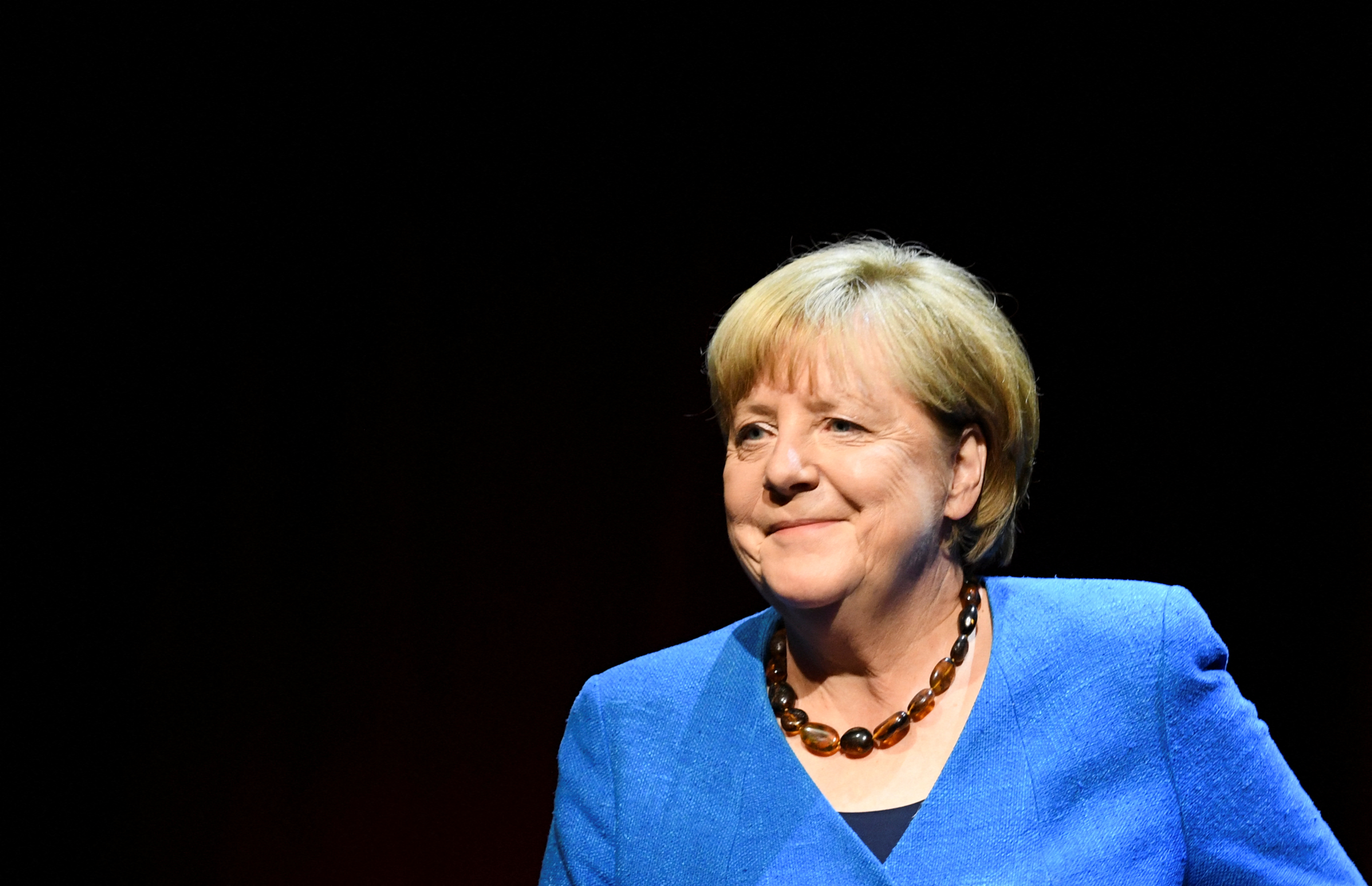 Angela Merkel in bright blue jacket with a bead necklace.