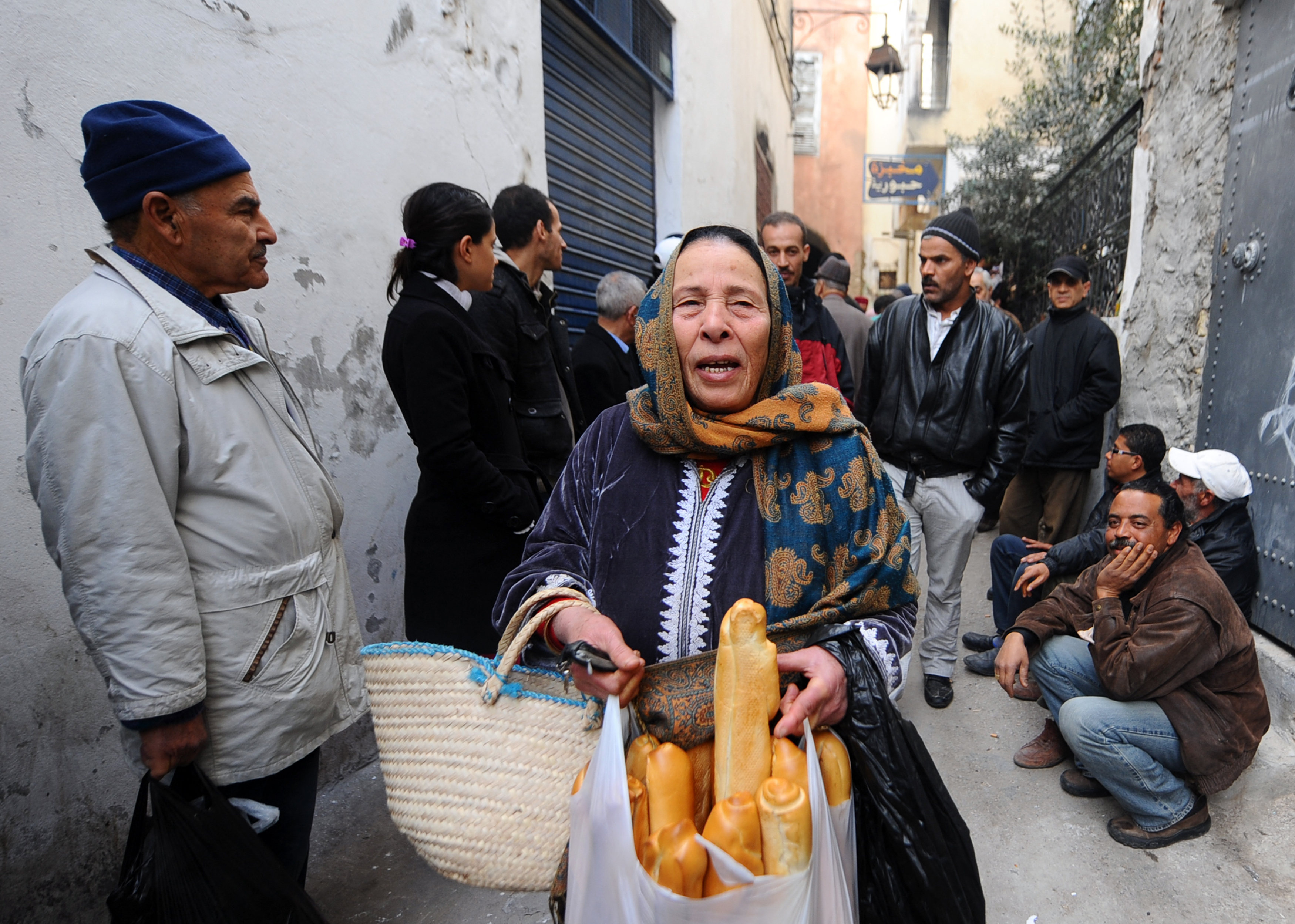 A woman shows bread she just bought while others queue up to buy some bread in Tunis's Medina on January 16, 2011.