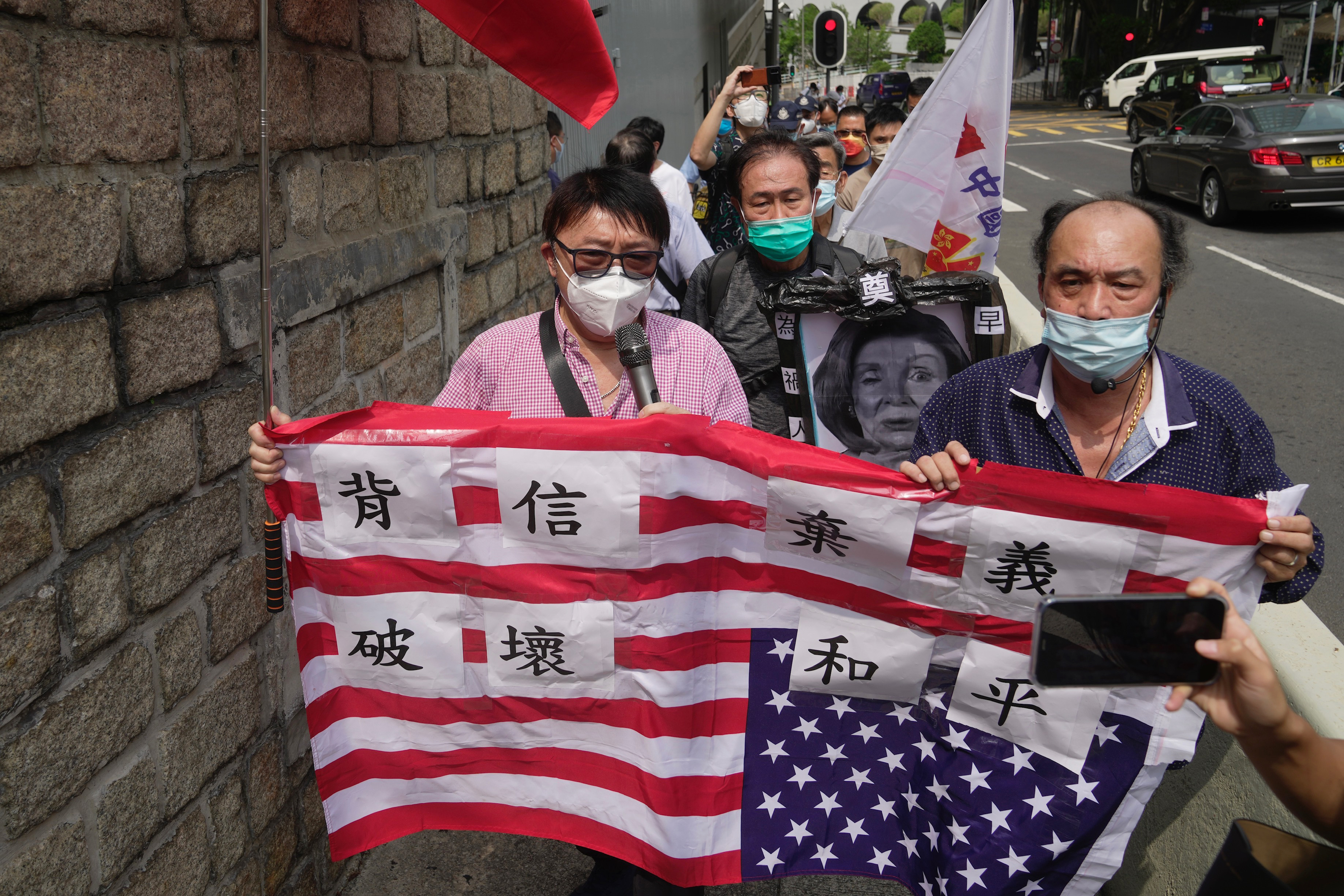 Pro-China supporters hold U.S. flag and a picture of U.S. House Speaker Nancy Pelosi during a protest outside the Consulate General of the United States in Hong Kong, Wednesday, Aug. 3, 2022.