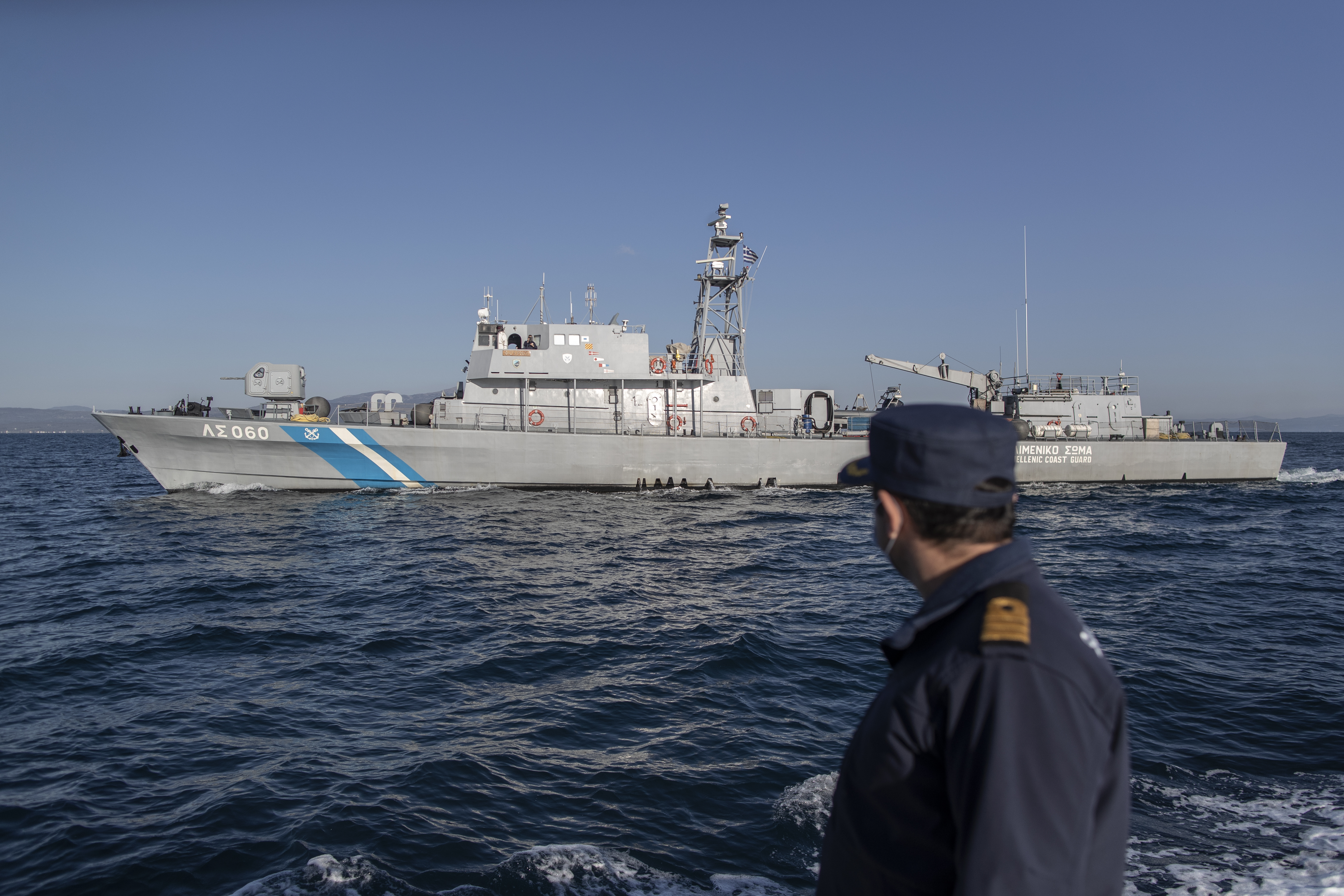 Greek coastguard member with a ship in the background at sea