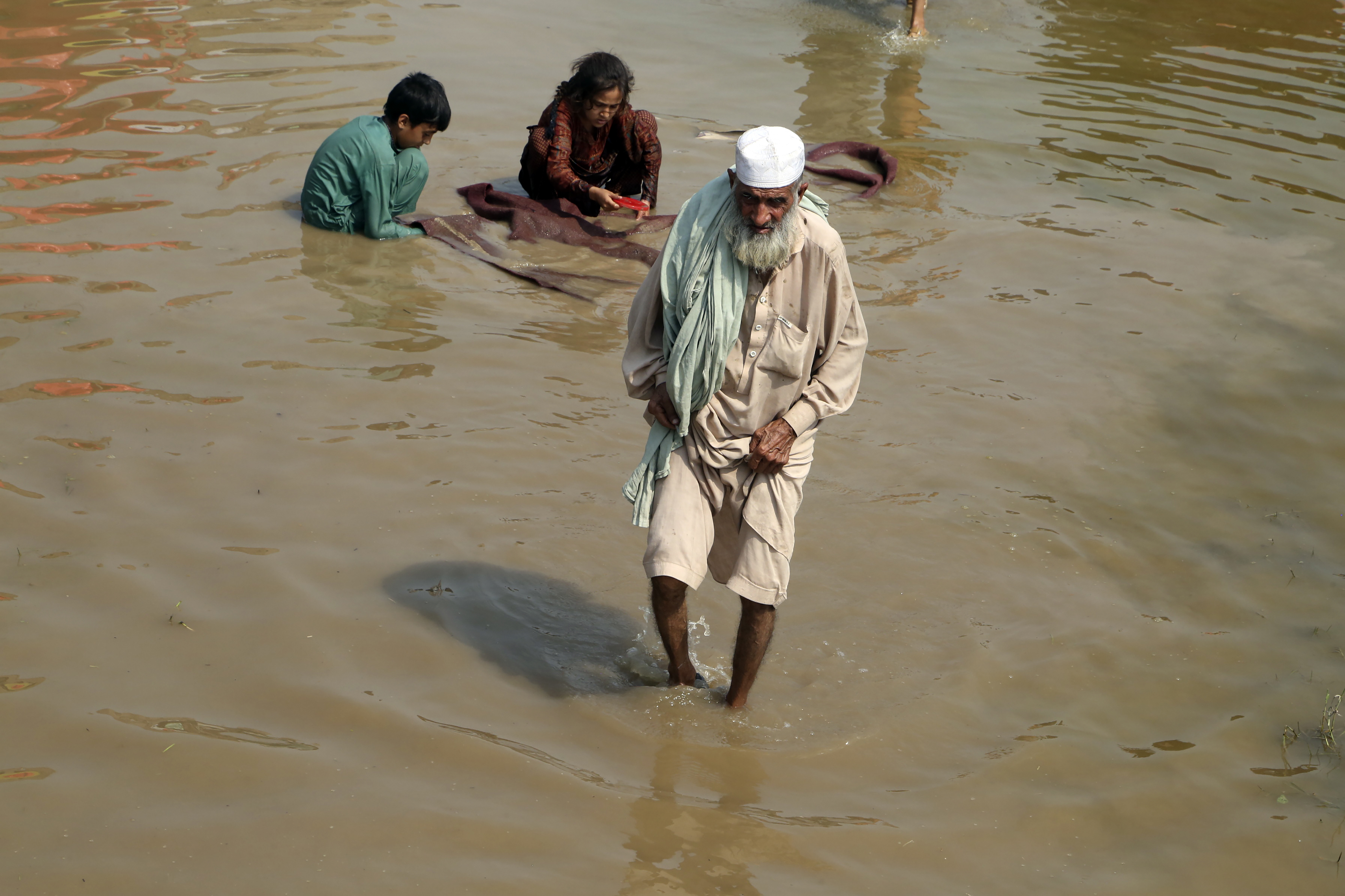 An elderly man wade through floodwaters in Charsadda, Pakistan, Thursday, Sept. 1, 2022. Pakistani health officials on Thursday reported an outbreak of waterborne diseases in areas hit by recent record-breaking flooding, as authorities stepped up efforts to ensure the provision of clean drinking water to hundreds of thousands of people who lost their homes in the disaster.