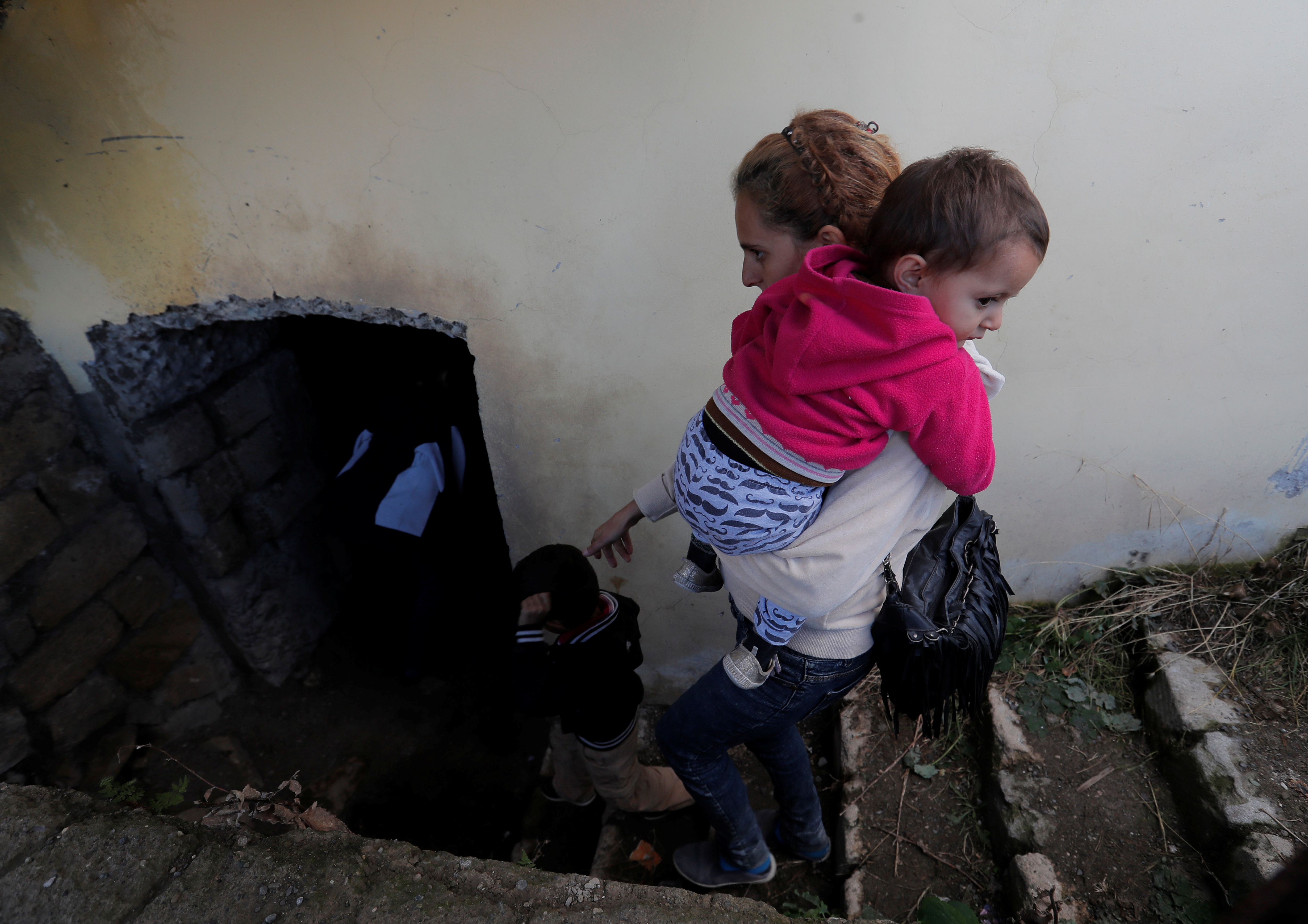 A woman and children go down to the basement of a building to take shelter during the fighting over the breakaway region of Nagorno-Karabakh, in Shushi (Shusha) October 8, 2020. REUTERS/Stringer