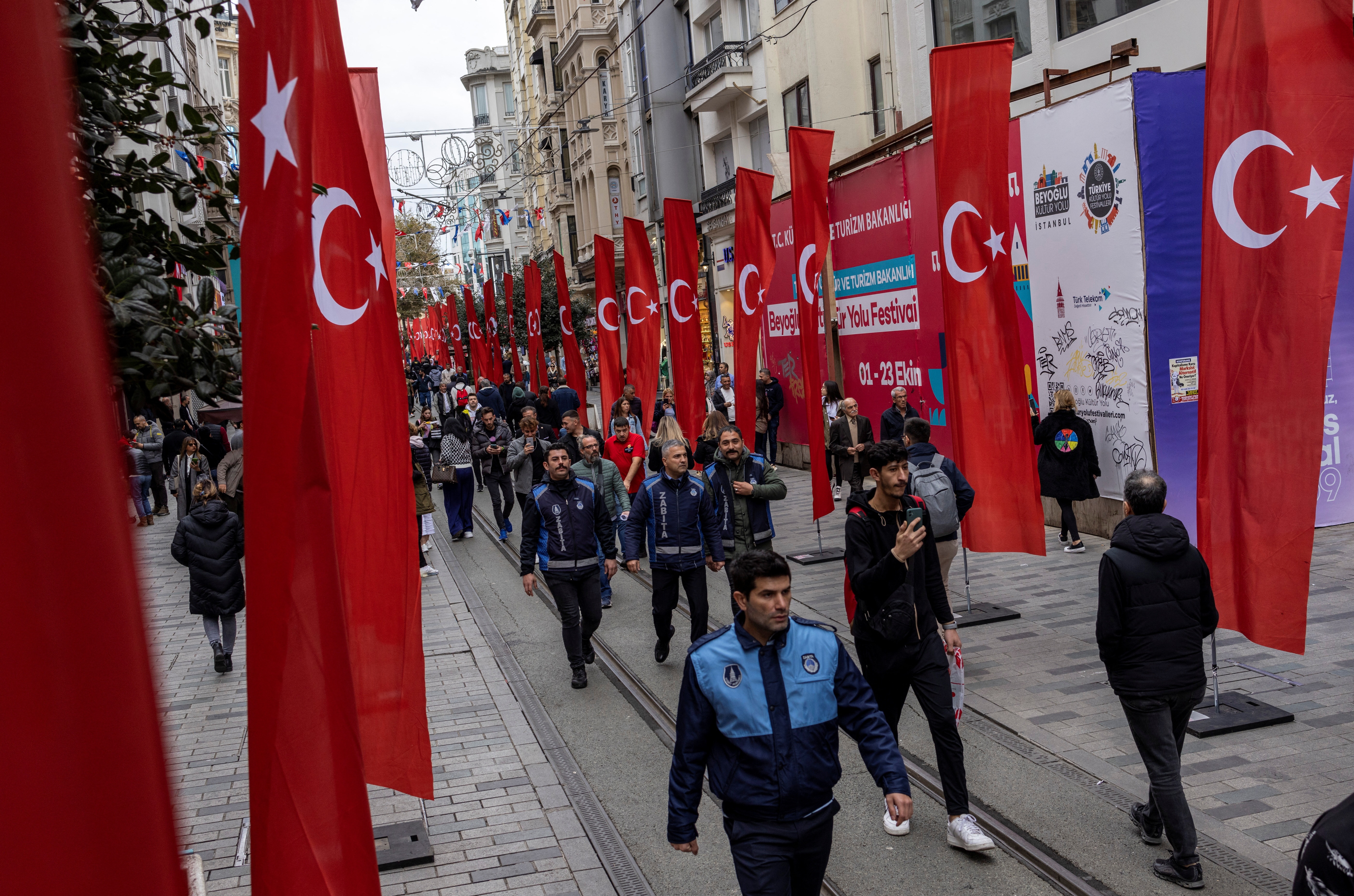 People walk along an Istiklal Avenue decorated with Turkish flags on November 14, 2022, a day after a deadly bombing [Umit Bektas/Reuters]