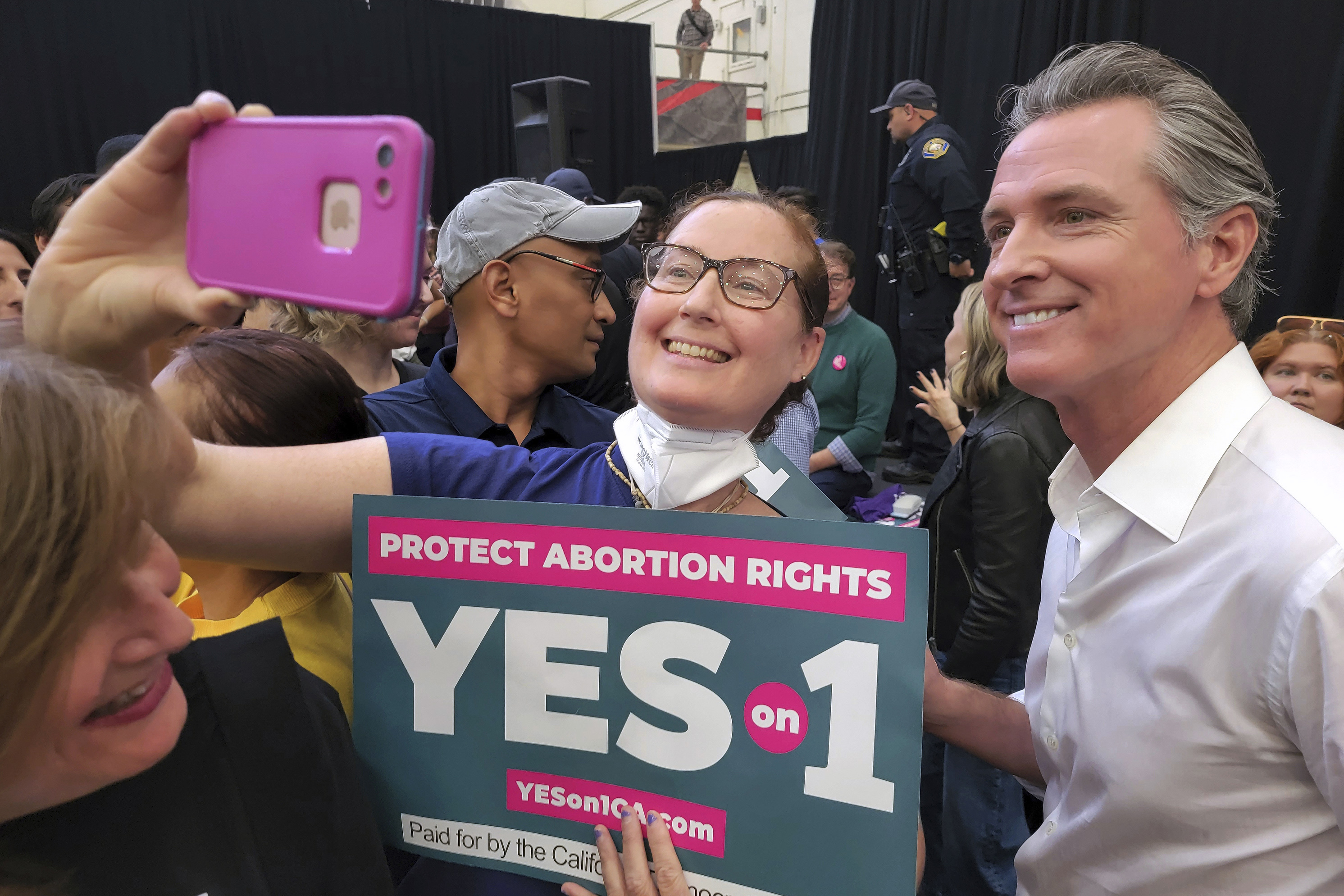 An abortion rights supporter takes a selfie with a "Yes on 1" sign and California governor Gavin Newsom.