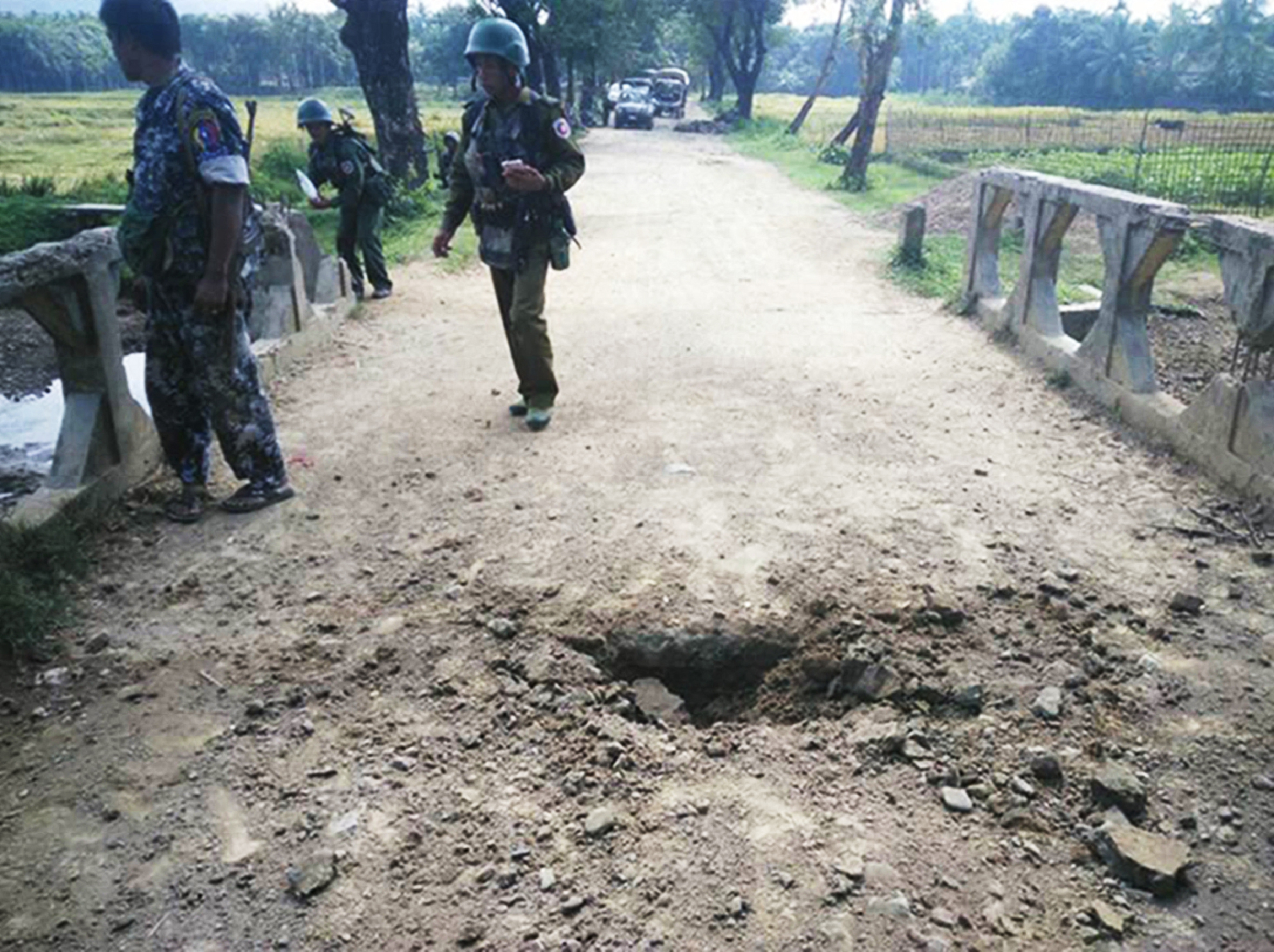 Myanmar soldiers view the crater from a landmine explosion on a bridge in Maung Nama Taung village of Maungdaw, located in Rakhine State near the Bangladesh border on November 12, 2016.
