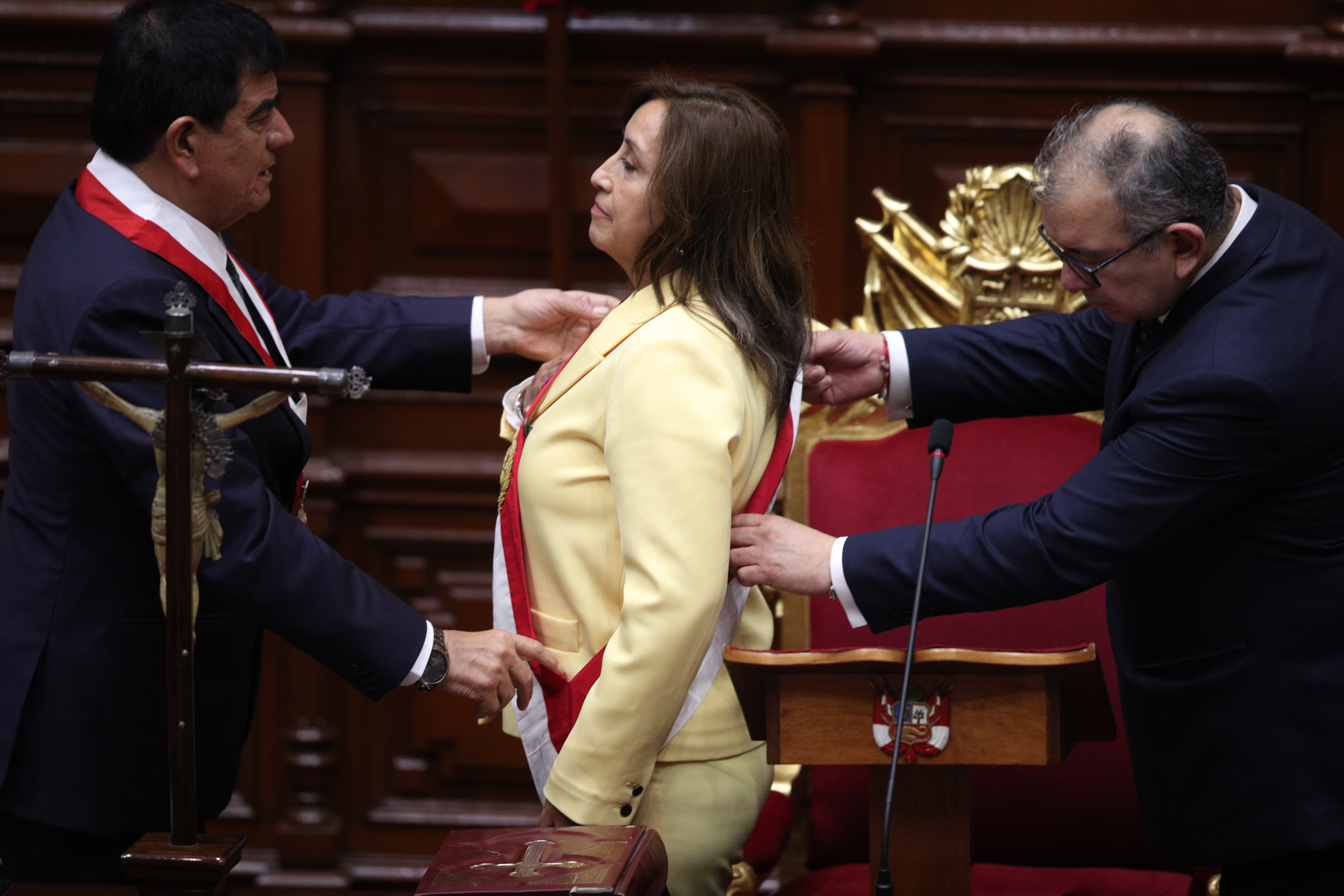 Former Vice President Dina Boluarte receives the presidential sash as she is sworn-in as the new president at Congress in Lima, Peru, Wednesday, Dec. 7, 2022. Peru's Congress voted to remove President Pedro Castillo from office Wednesday and replace him with the vice president, shortly after Castillo tried to dissolve the legislature ahead of a scheduled vote to remove him. At left is Congress President Jose Williams and at right is Jose Cevasco. (AP Photo/Guadalupe Pardo)