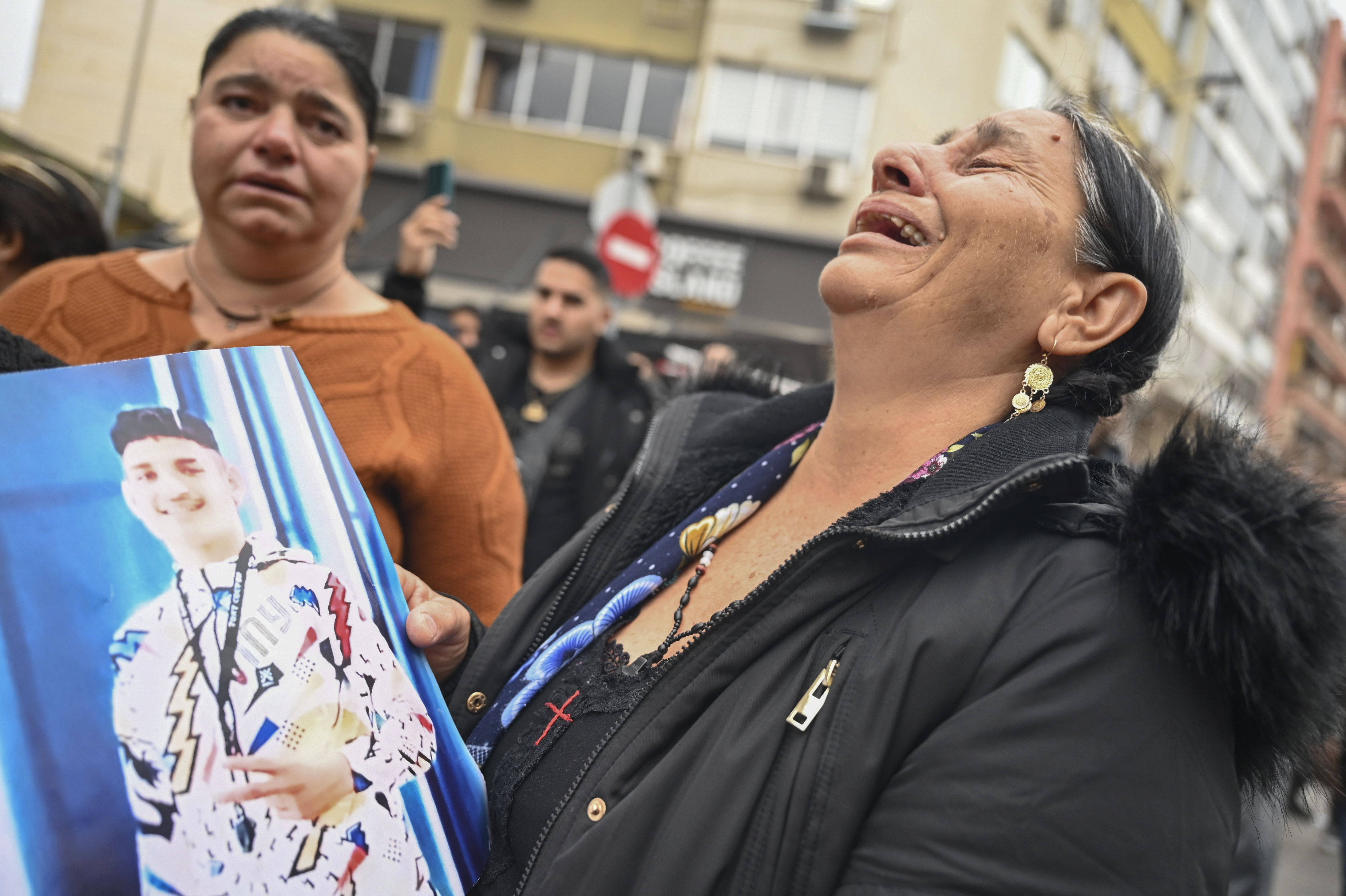 A woman reacts as she holds a photo of an injured 16-year-old teenager while relatives and other protesters from the Roma community protest outside the courthouse in Greece's second largest city of Thessaloniki