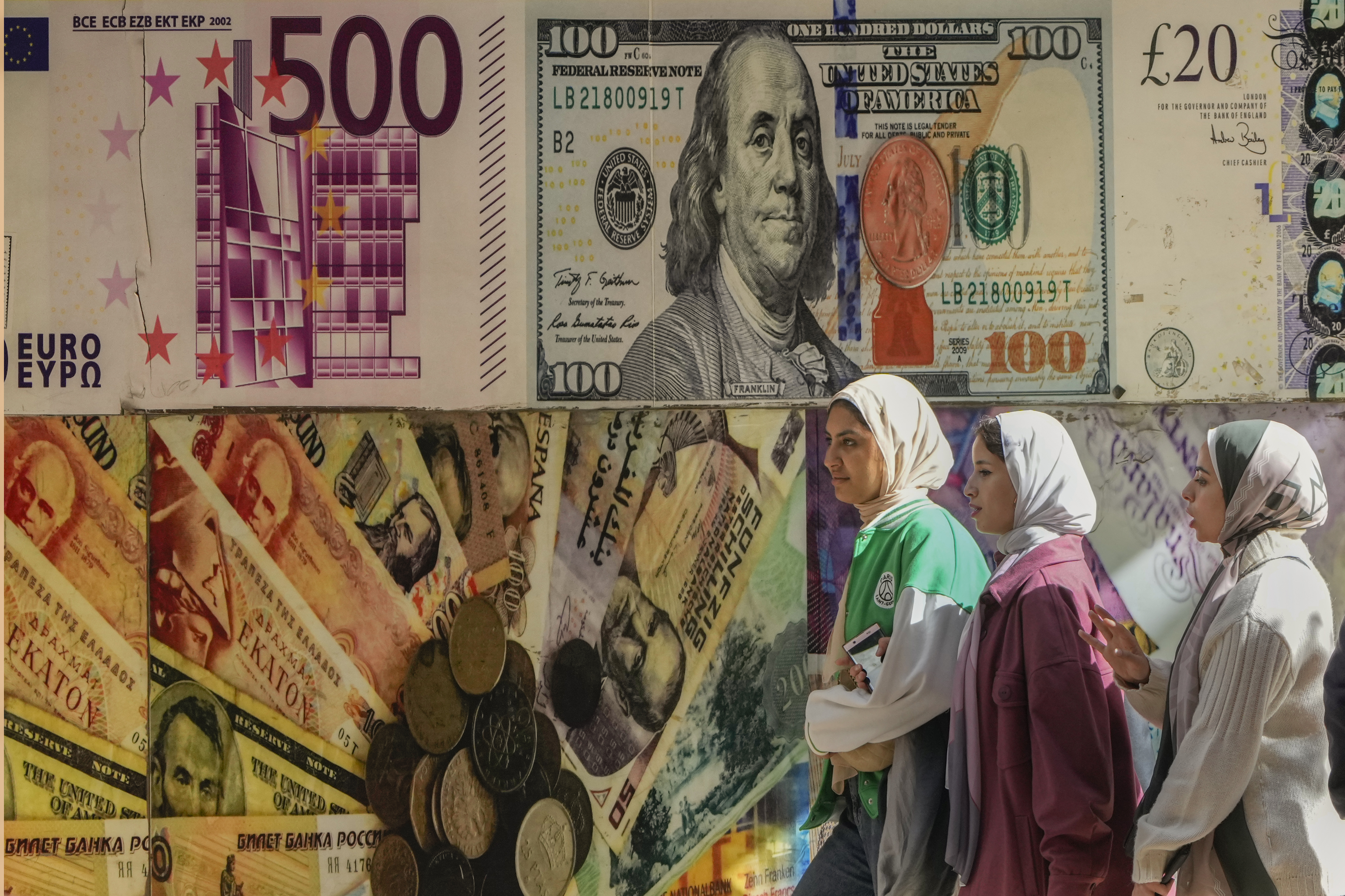 Egyptians walk past a poster depicting U.S. dollar