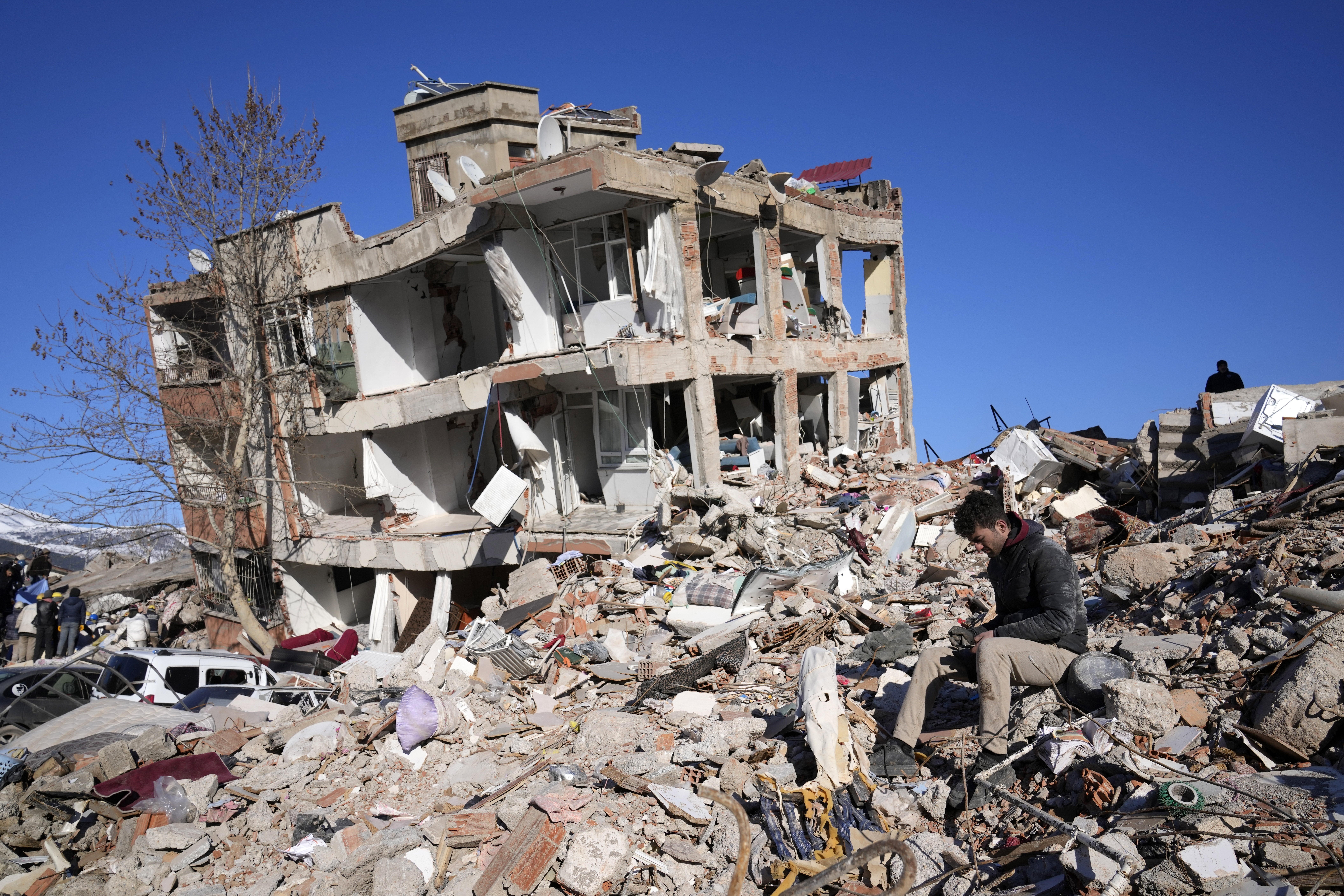 A man sits at his destroyed house