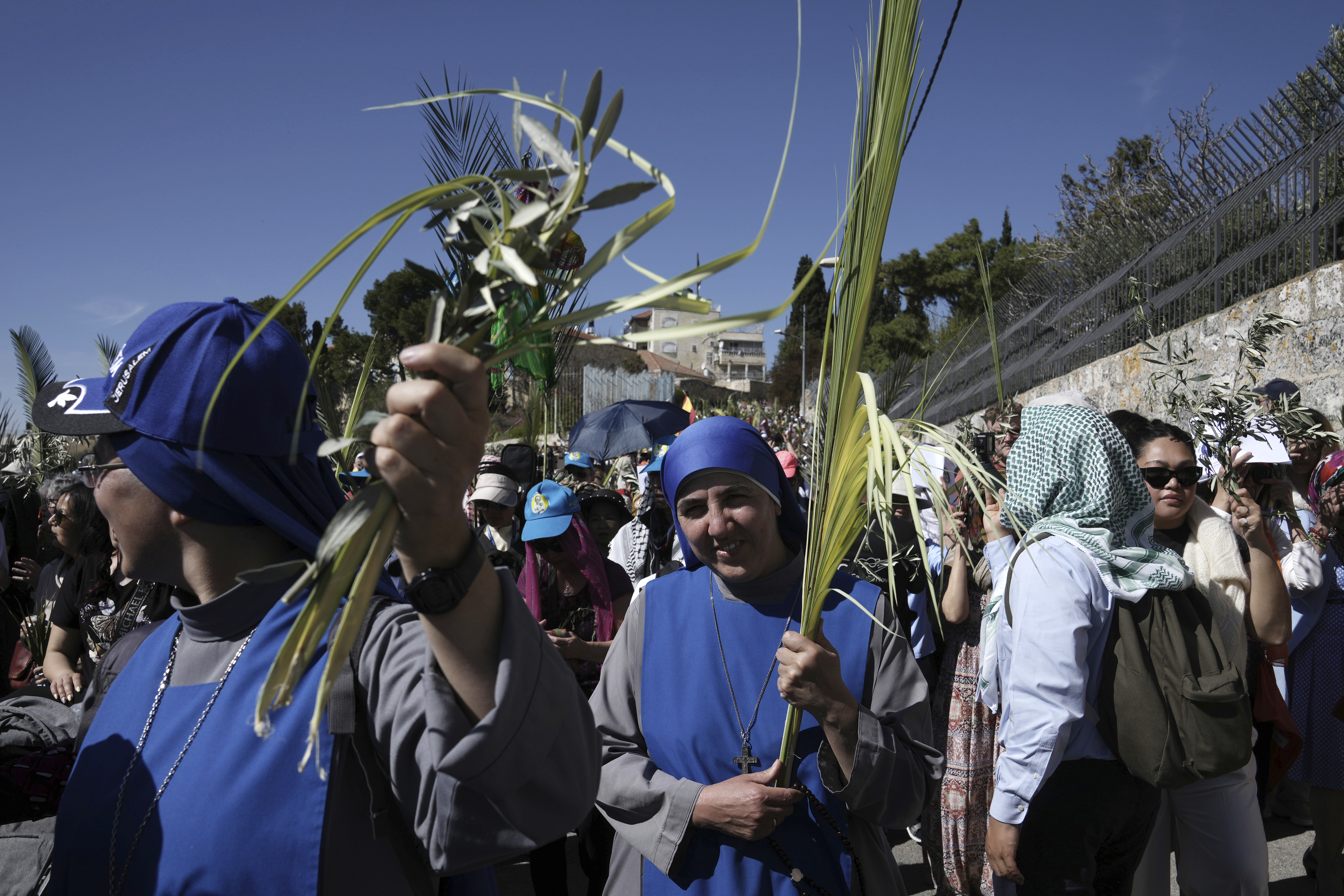 Nuns carry palm fronds as Christians walk in the Palm Sunday procession
