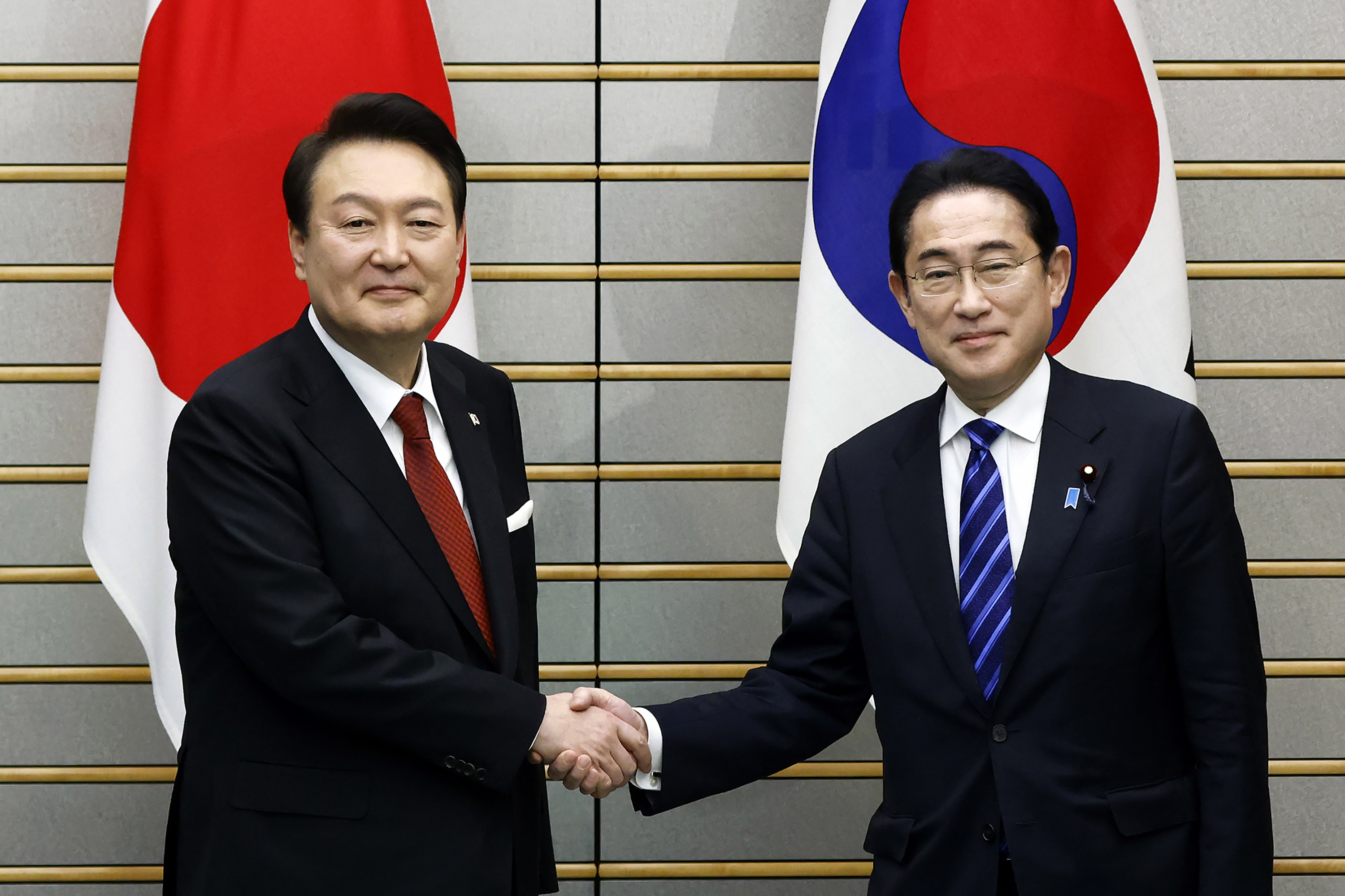 South Korean President Yoon Suk-yeol and Japanese Prime Minister Fumio Kishida shake hands ahead of their bilateral meeting at the prime minister's office in Tokyo, March 16, 2023.