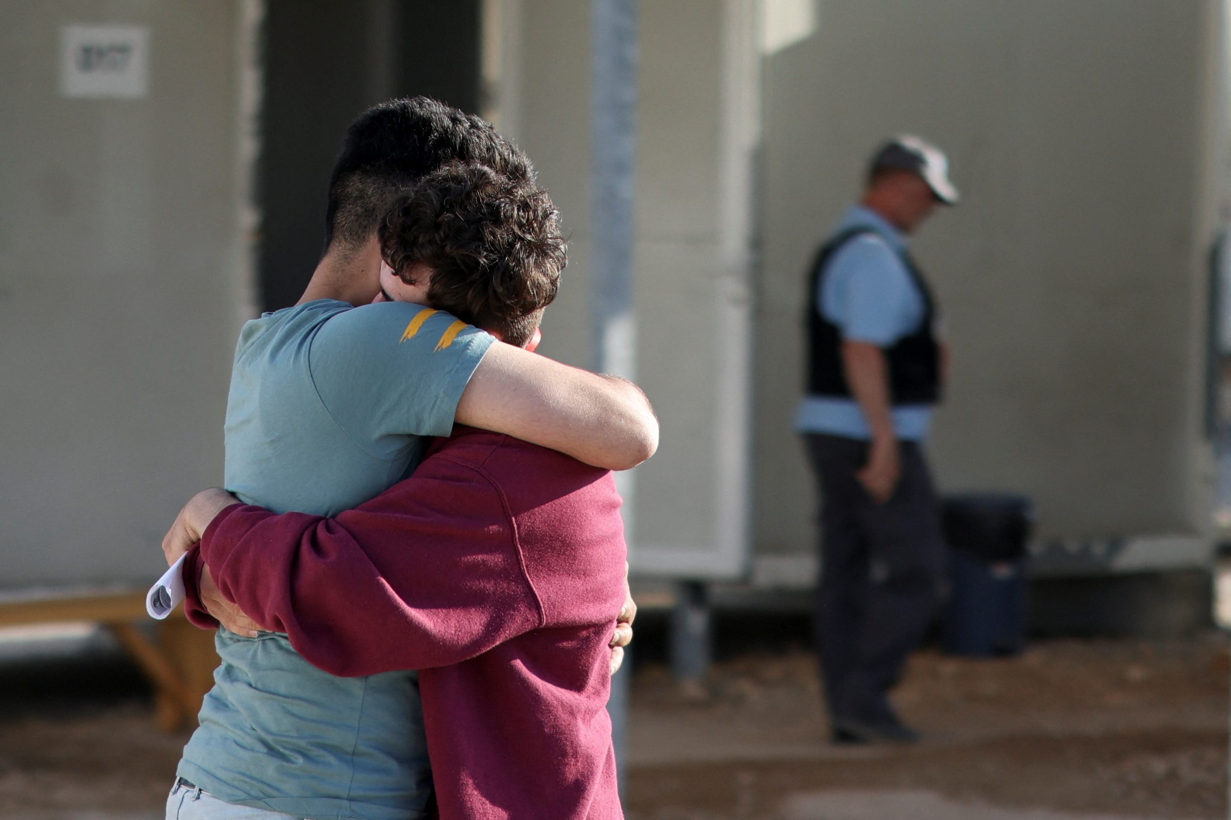 A Syrian survivor reunites with his brother at a reception and identification camp in Malakasa, Greece [Stelios Misinas/Reuters]