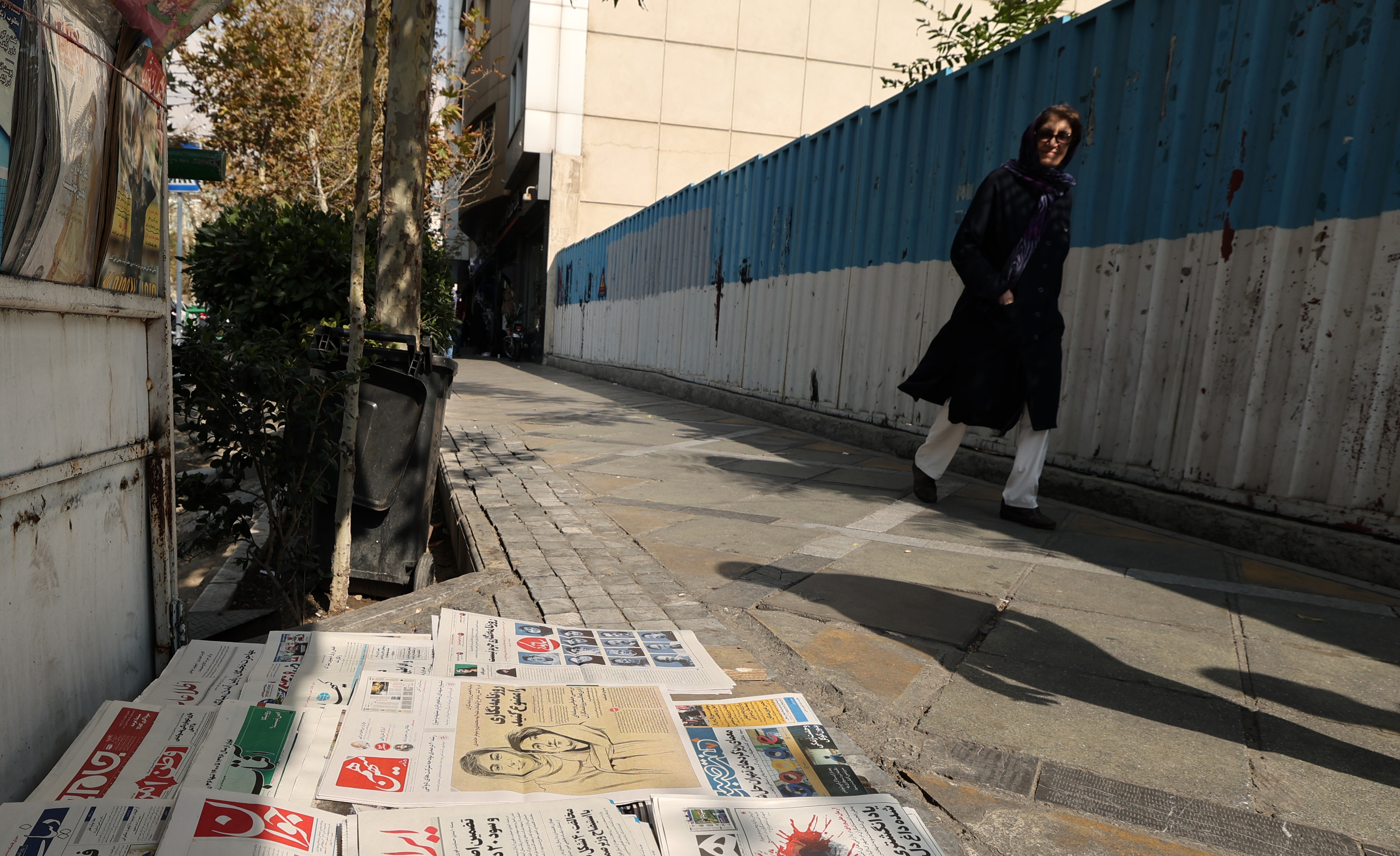 A woman walks past a kiosk in Tehran