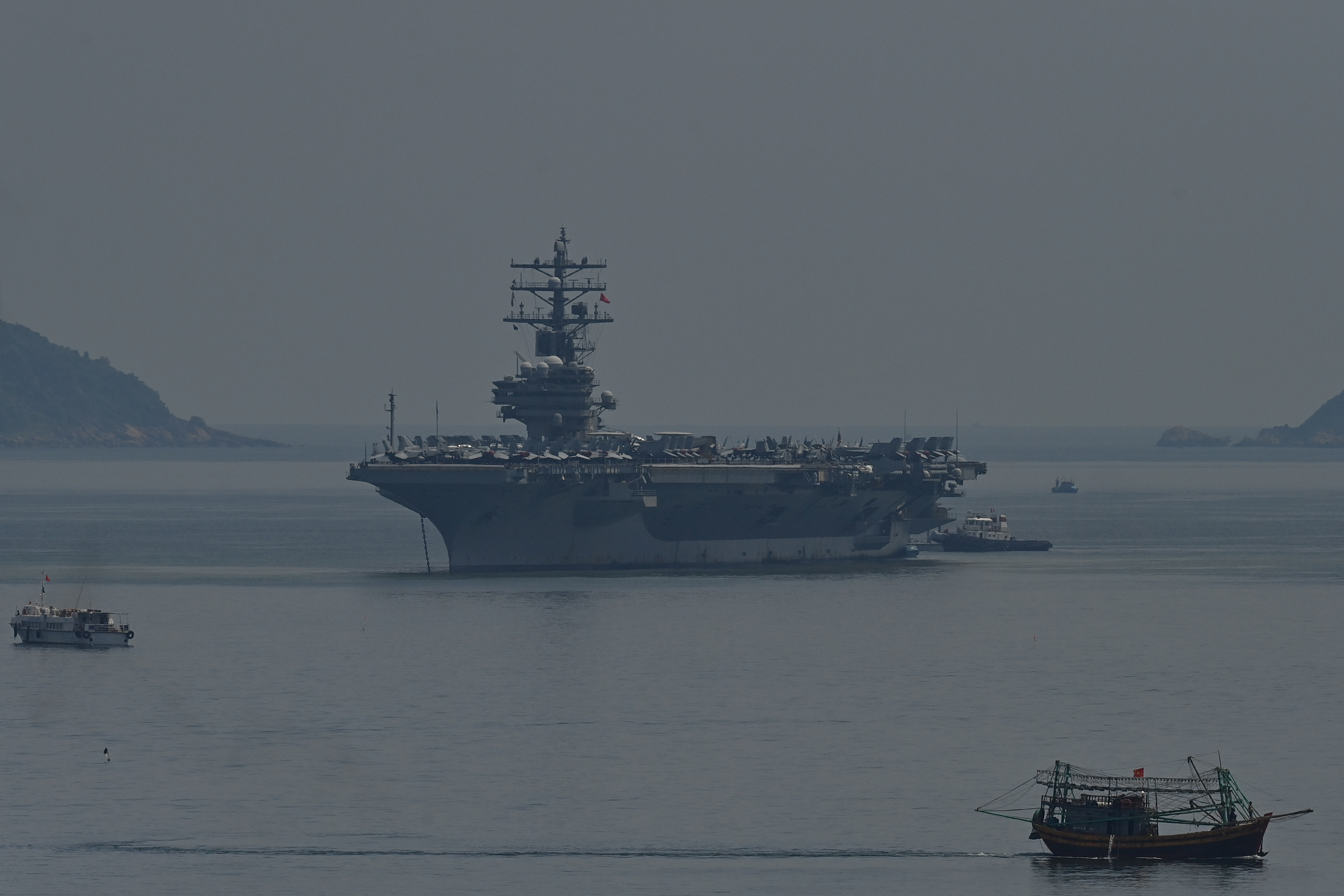 A Vietnamese fishing boat (R) sails past the USS Ronald Reagan off Danang