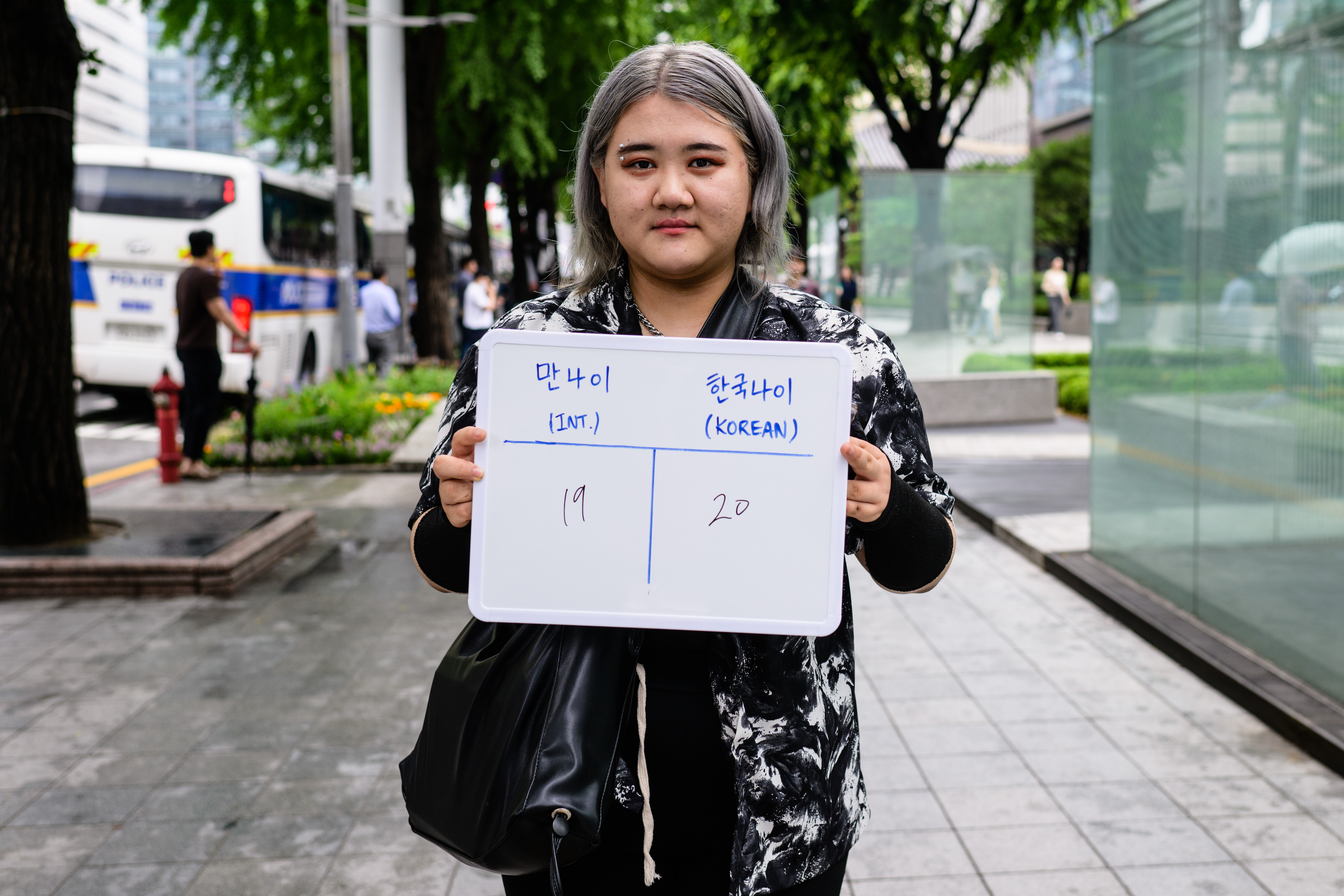 Kim Hye-rim, a university student studying computer science, poses with a whiteboard showing her international age, 19, and Korean age, 20