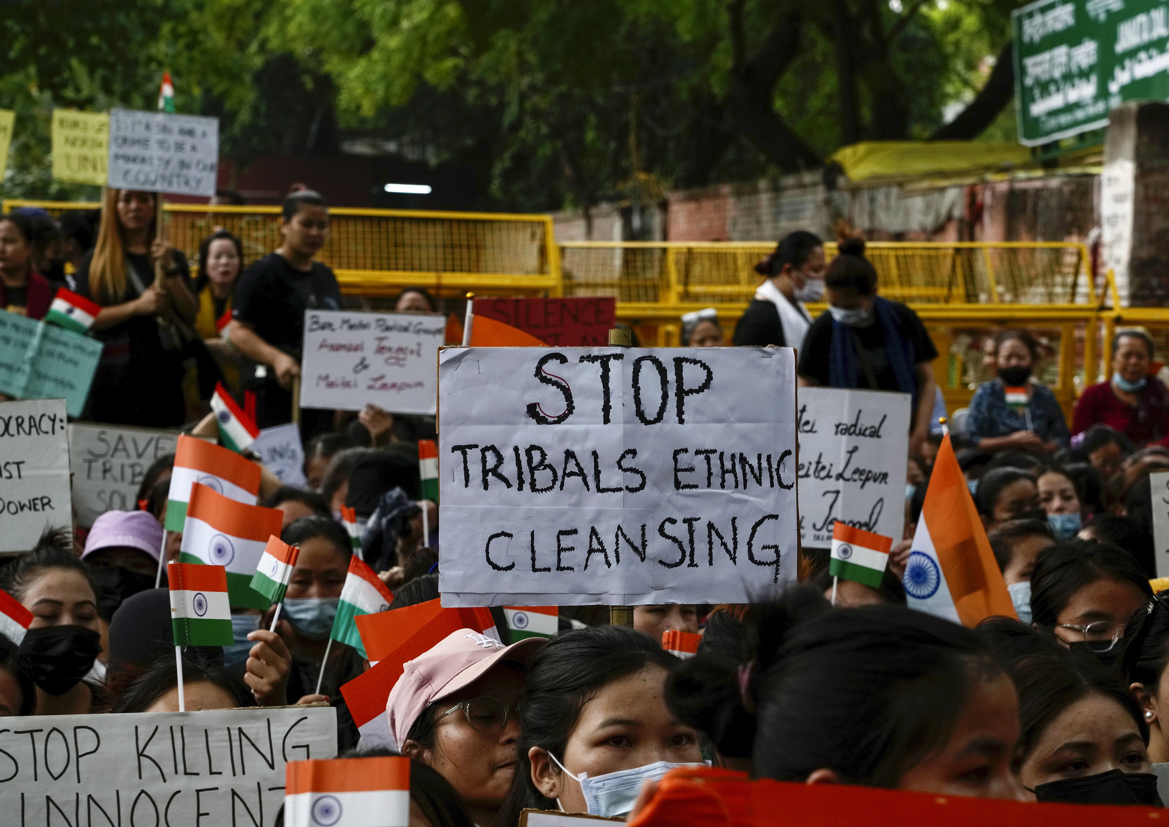 Members of the Kuki tribe protesting against the killing of tribals in their northeastern home state of Manipur, hold Indian flags and placards during a sit in protest in New Delhi, India, Monday, May 29, 2023. Manipur, which borders Myanmar, has been roiled by violence since 3 May after members of tribal groups clashed with a non-tribal group over demands of economic benefits and reservation status. More shootings and arson were reported Monday from the northeastern state, where dozens have been killed and more than 35,000 displaced following the worst ethnic clashes seen in decades. (AP Photo/Manish Swarup)