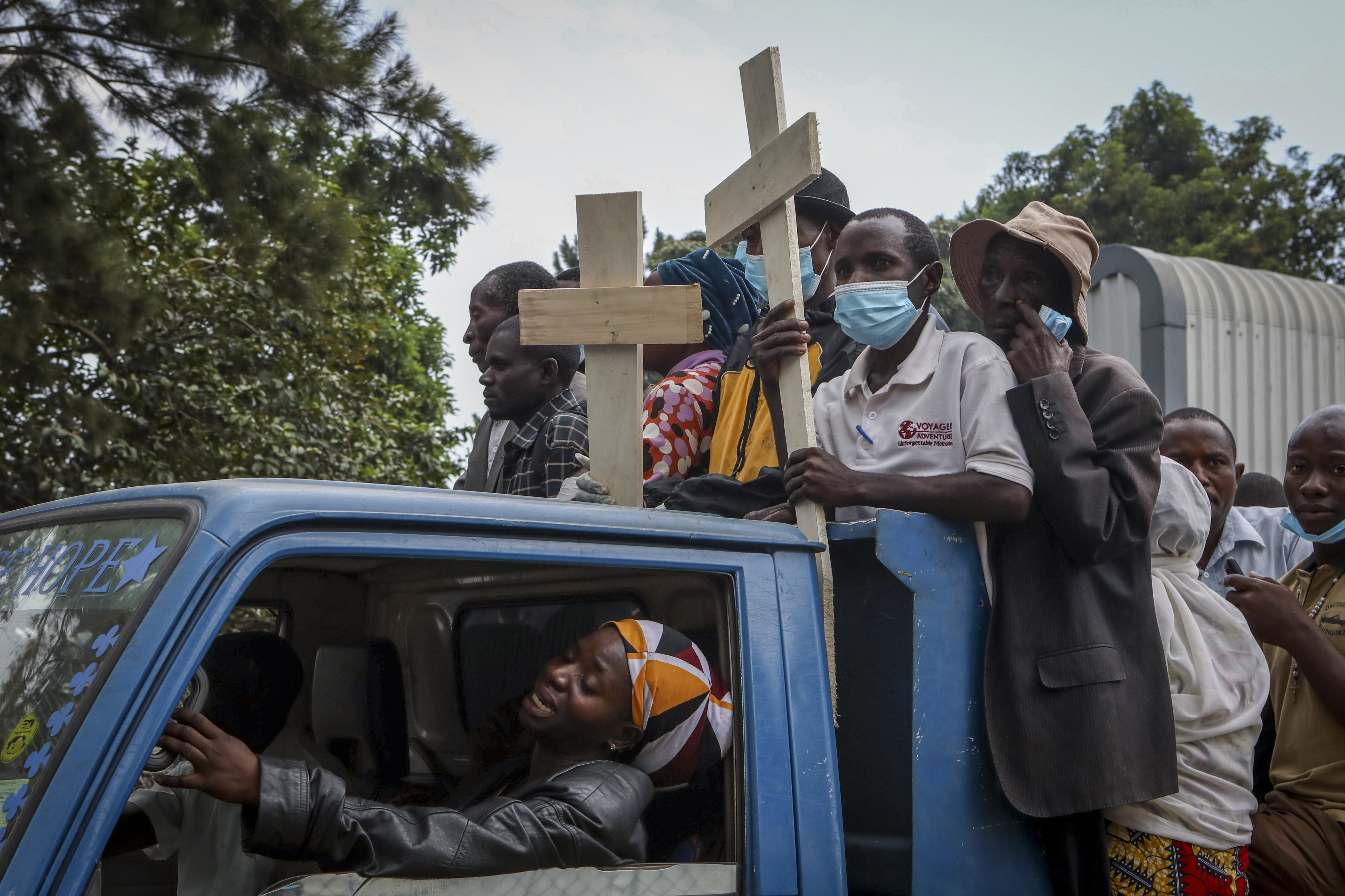Relatives ride in the back of a truck with the coffins of villagers killed by suspected rebels who attacked Lhubiriha Secondary School in Mpondwe, Uganda [File: Hajarah Nalwadda/AP Photo]