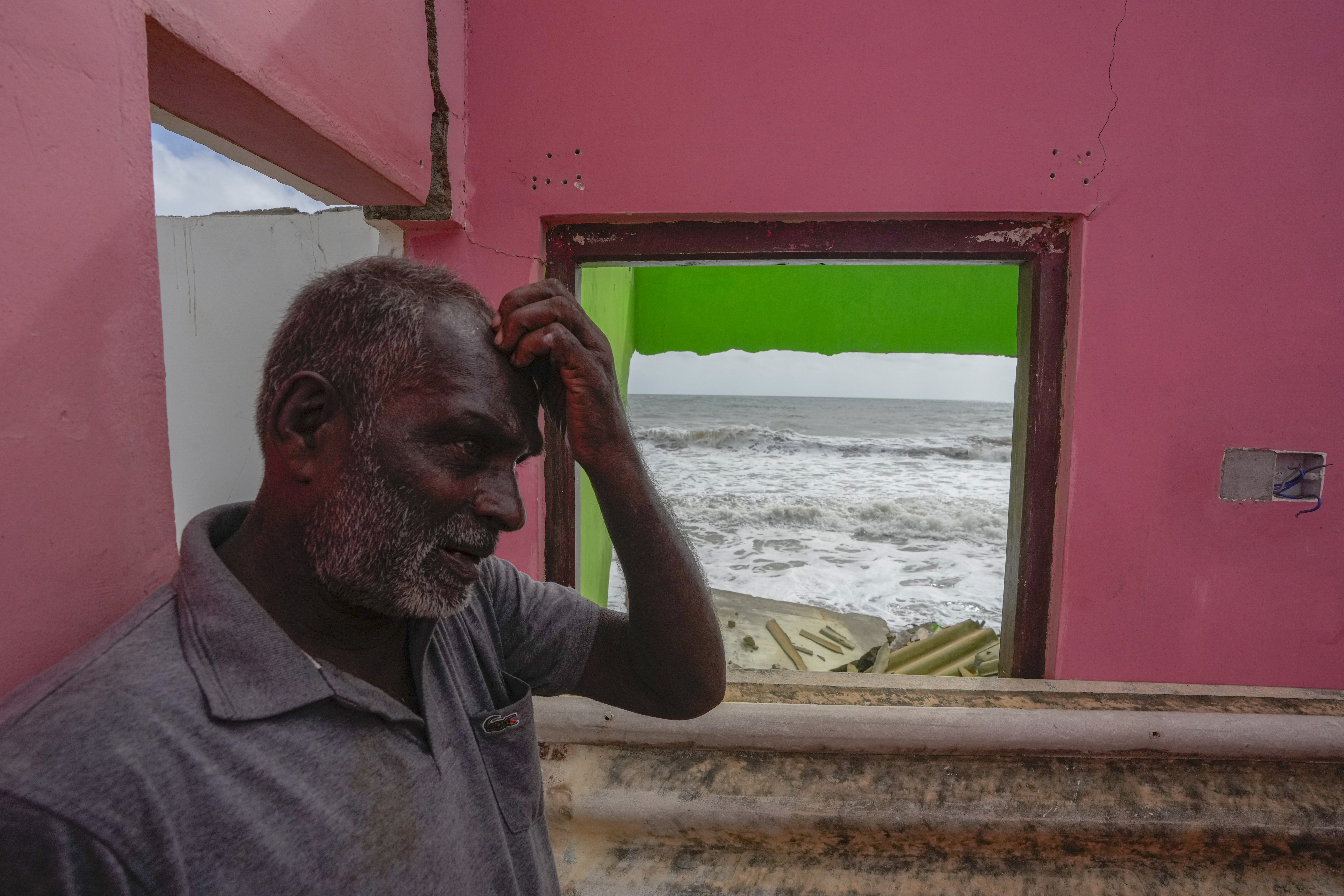 Ranjith Sunimal Fernando gestures as he looks for salvageable items at his home destroyed by erosion in Iranawila