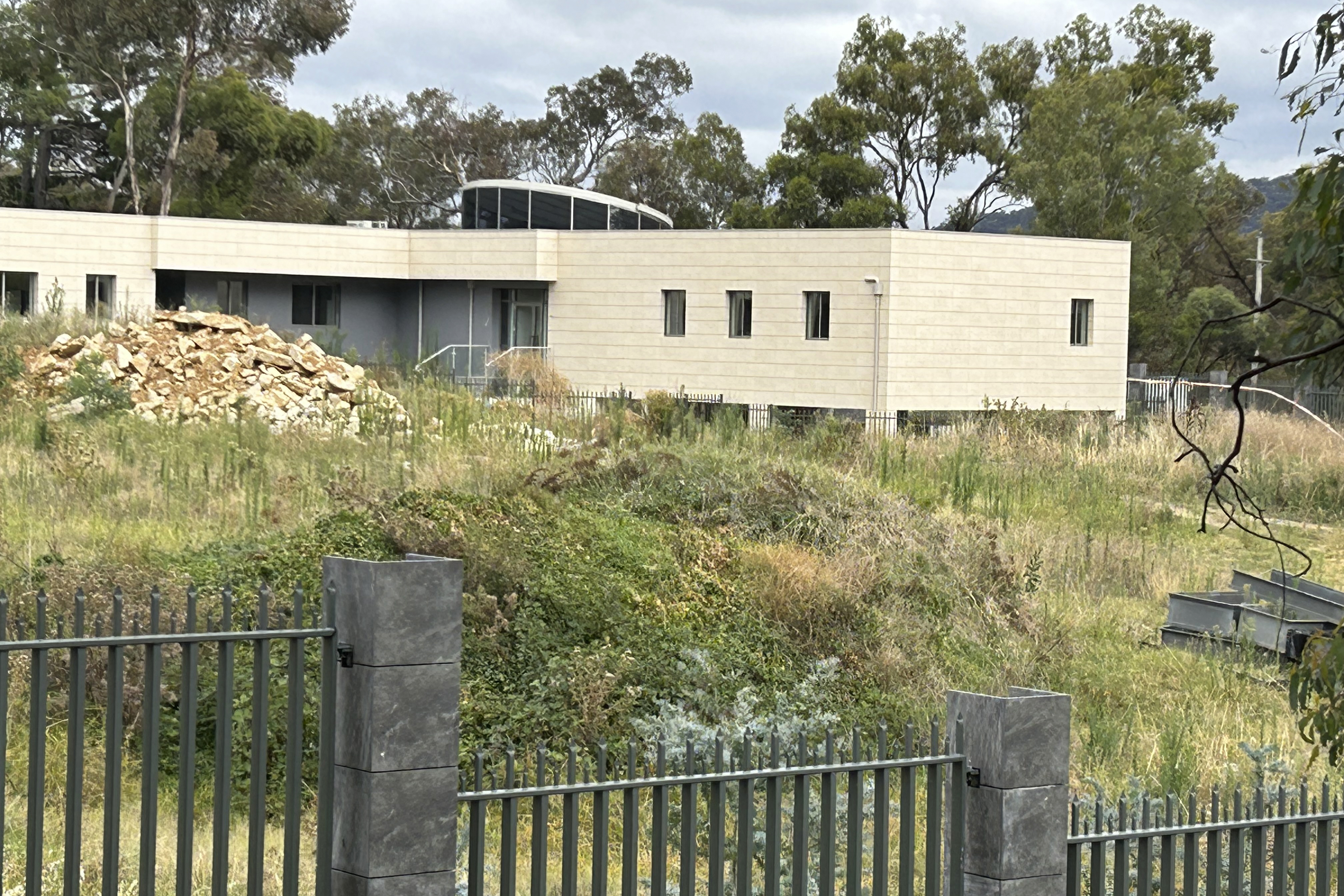 The site of the proposed Russian embassy in Canberra. There is a metal fence and a white half-built building behind.