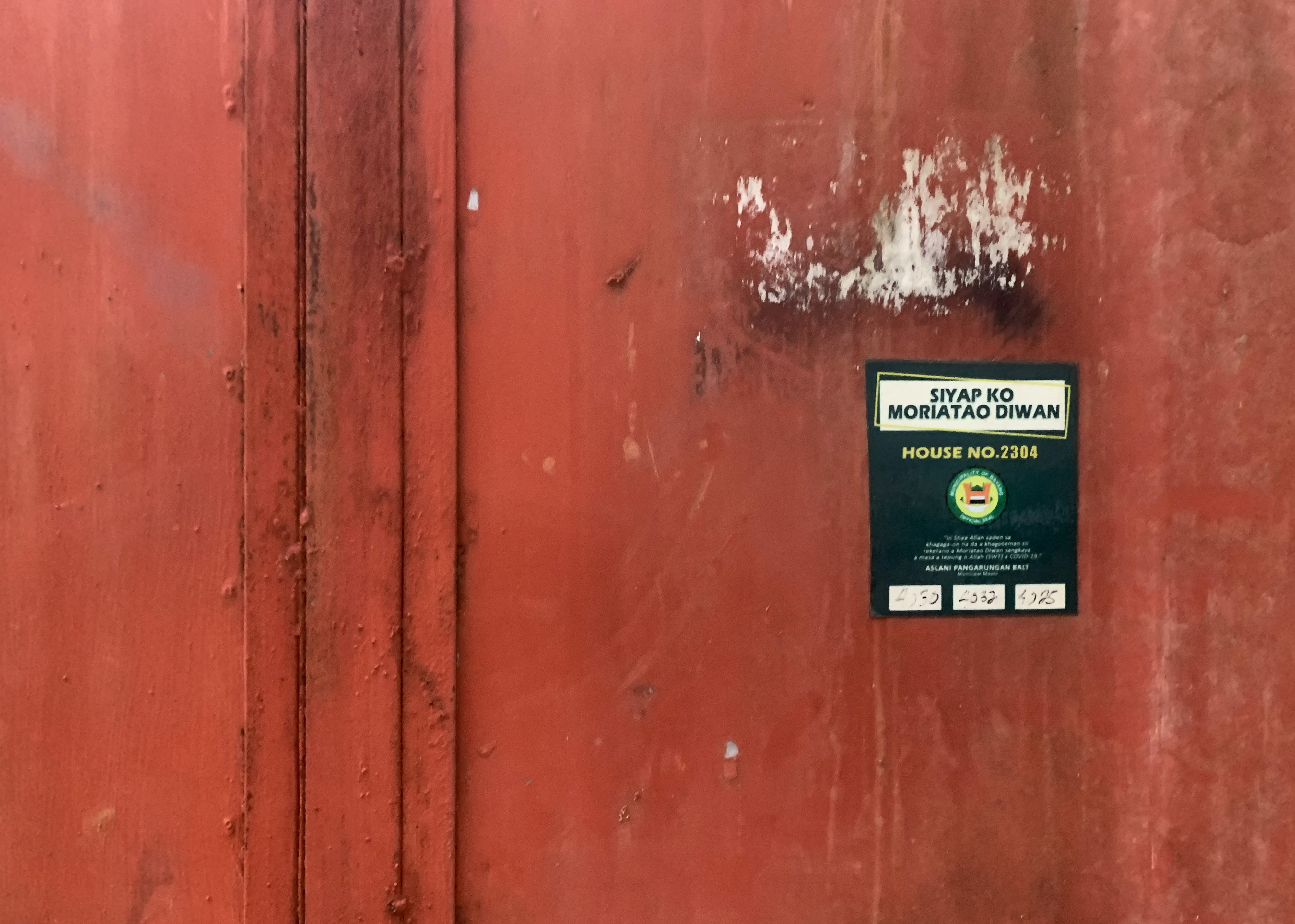 The red gate, with a a sticker showing the house number, where Zacharia was holed up.