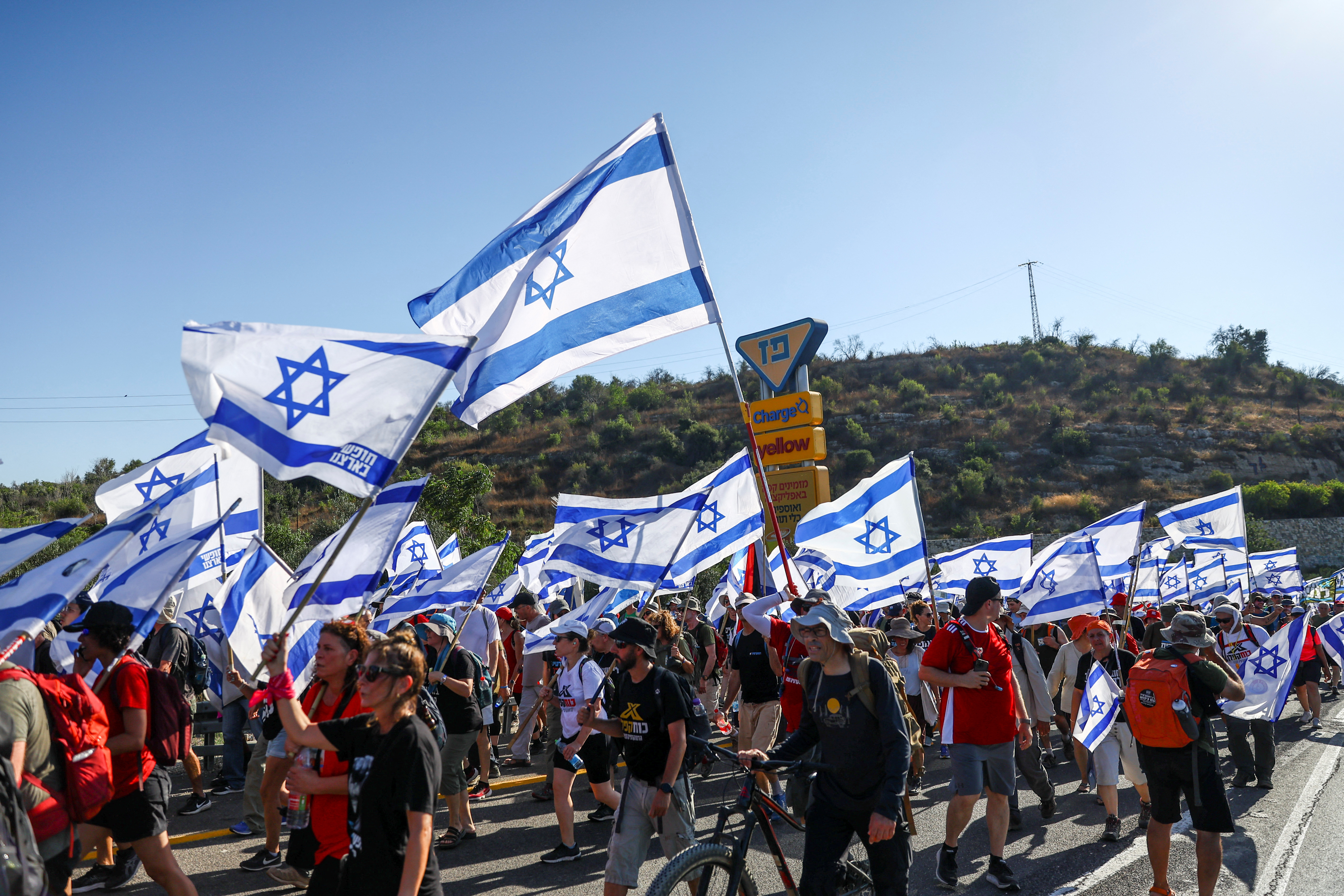 Protesters hold Israeli flags as they march in demonstration against Israeli Prime Minister Benjamin Netanyahu and his nationalist coalition government's judicial overhaul on a road in Shoresh, Israel, which leads to Jerusalem