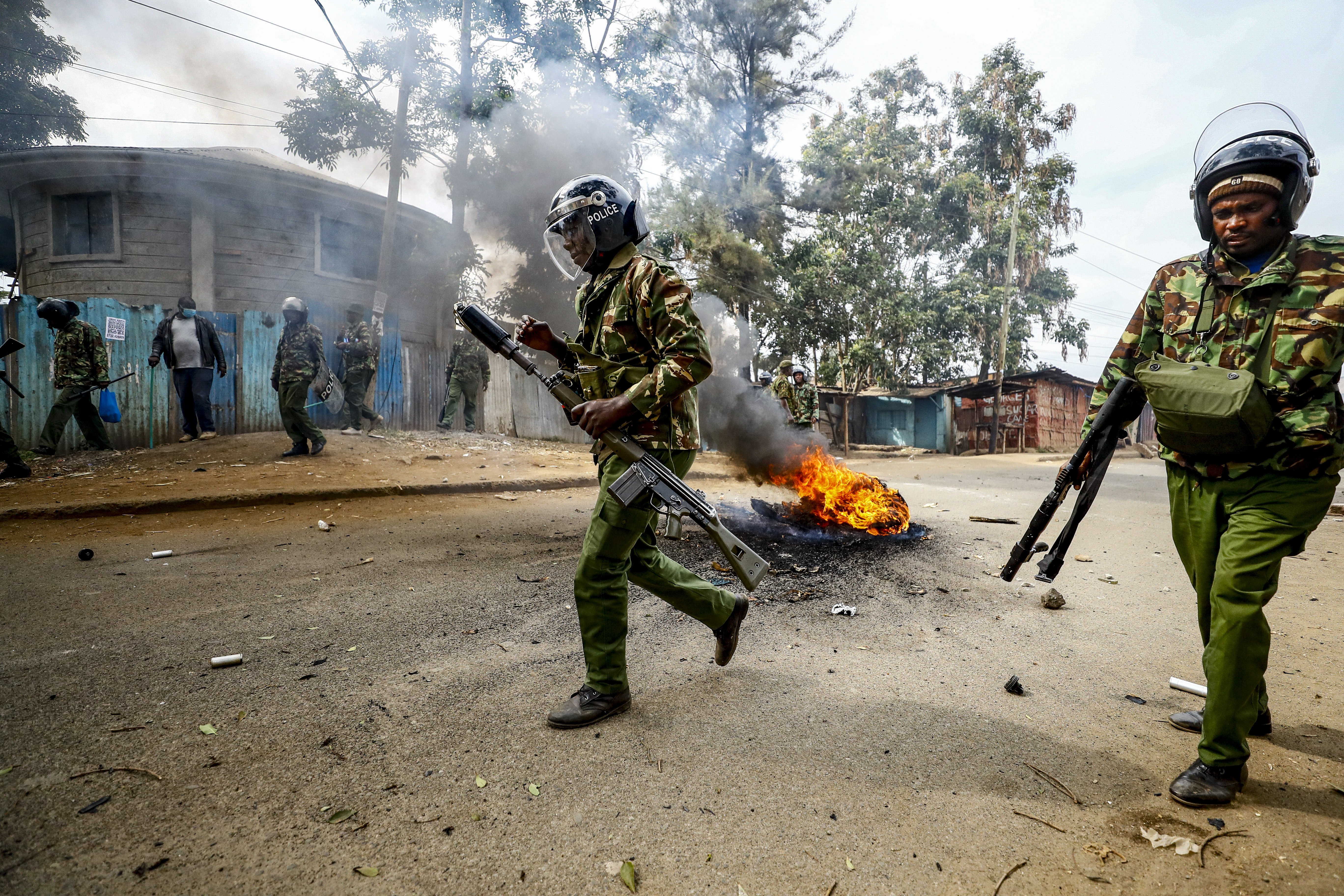 Riot policemen walk past a burning barricade
