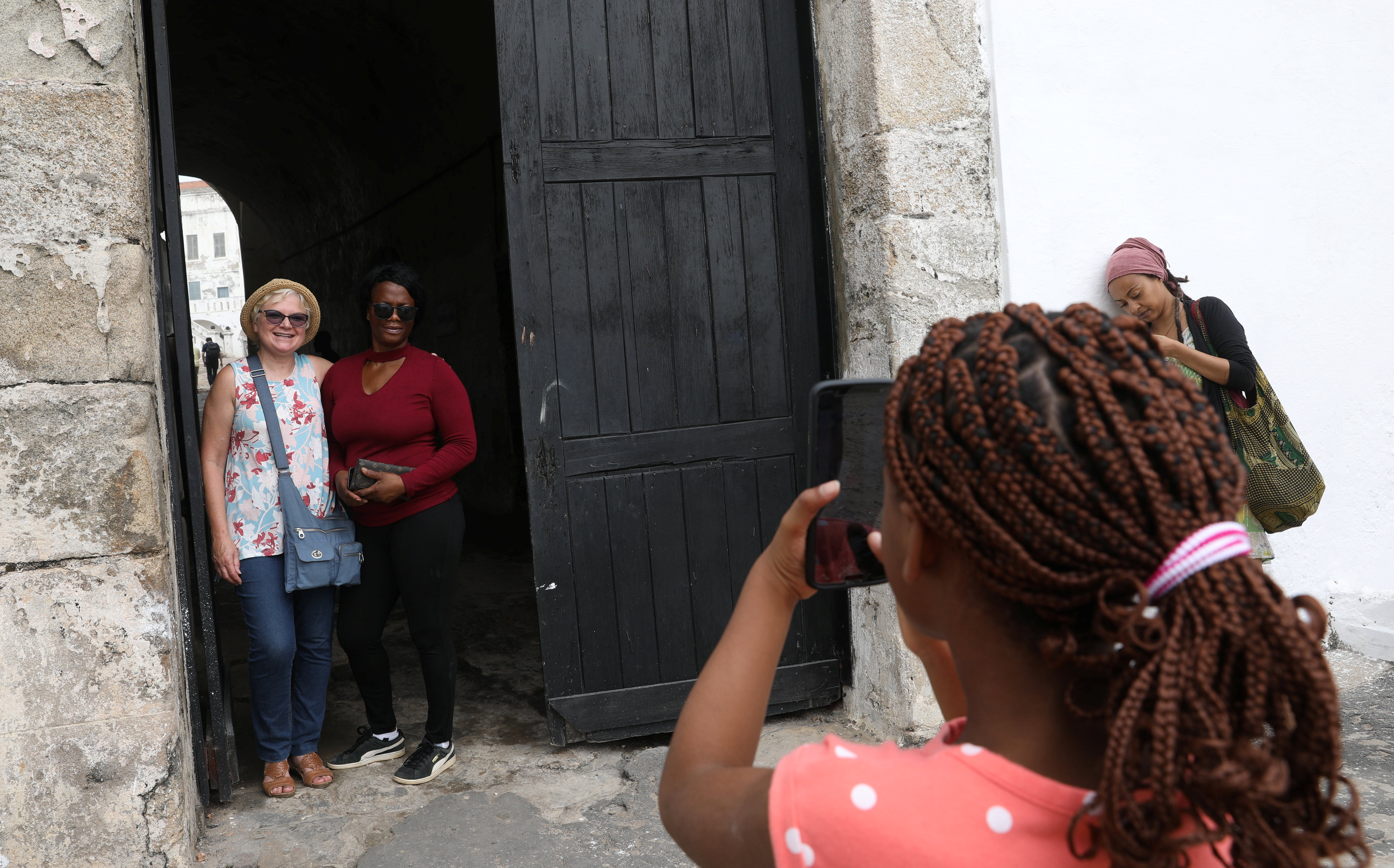 American tourist, Divine Koufahenou takes a picture of her Mother Afi and her friend Dawn Kravig at the 'Door of No Return' at the Cape Coast Slave Castle in Ghana