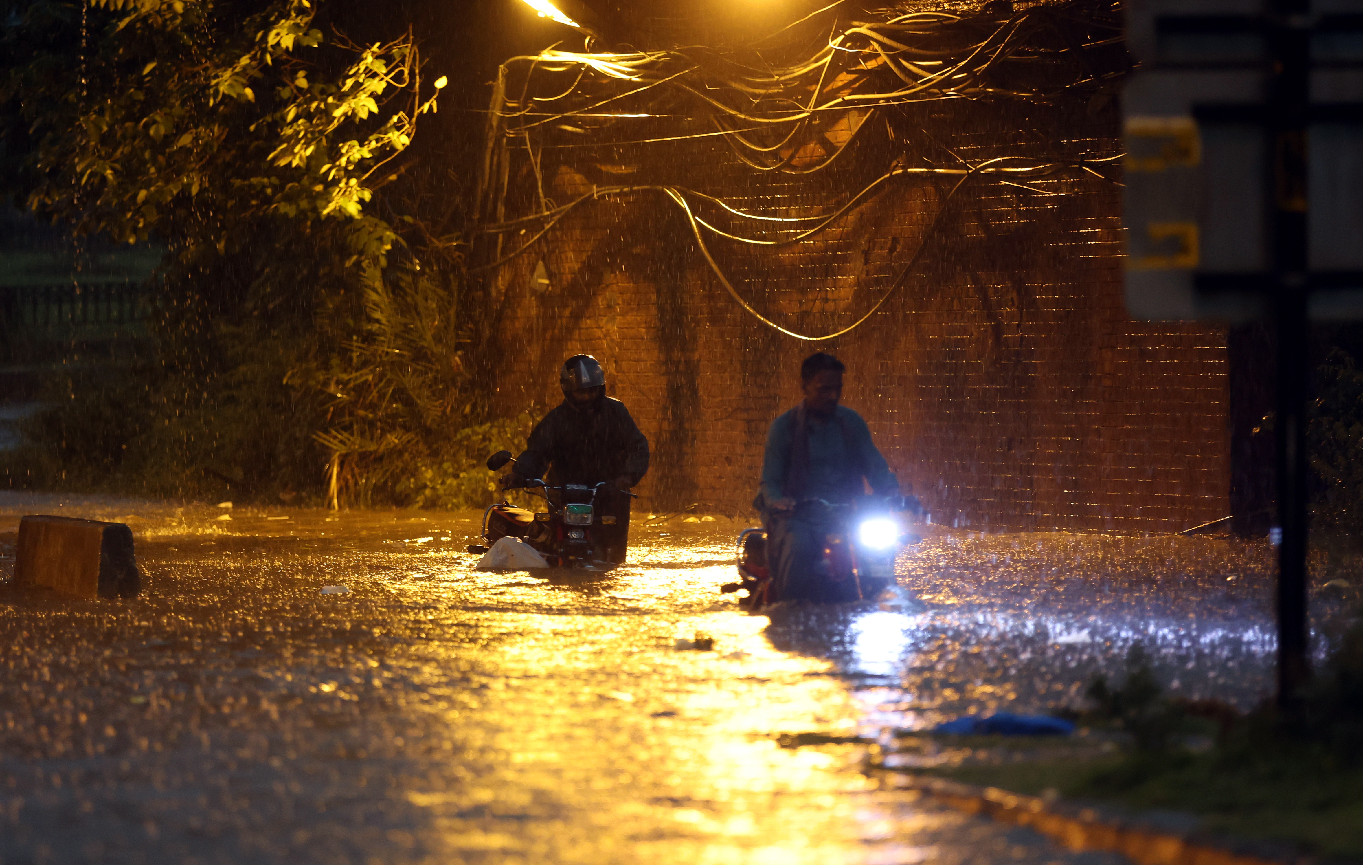 People make their way down a flooded road after heavy rains in Rawalpindi, Pakistan, in July [Sohail Shahzad/EPA-EFE]