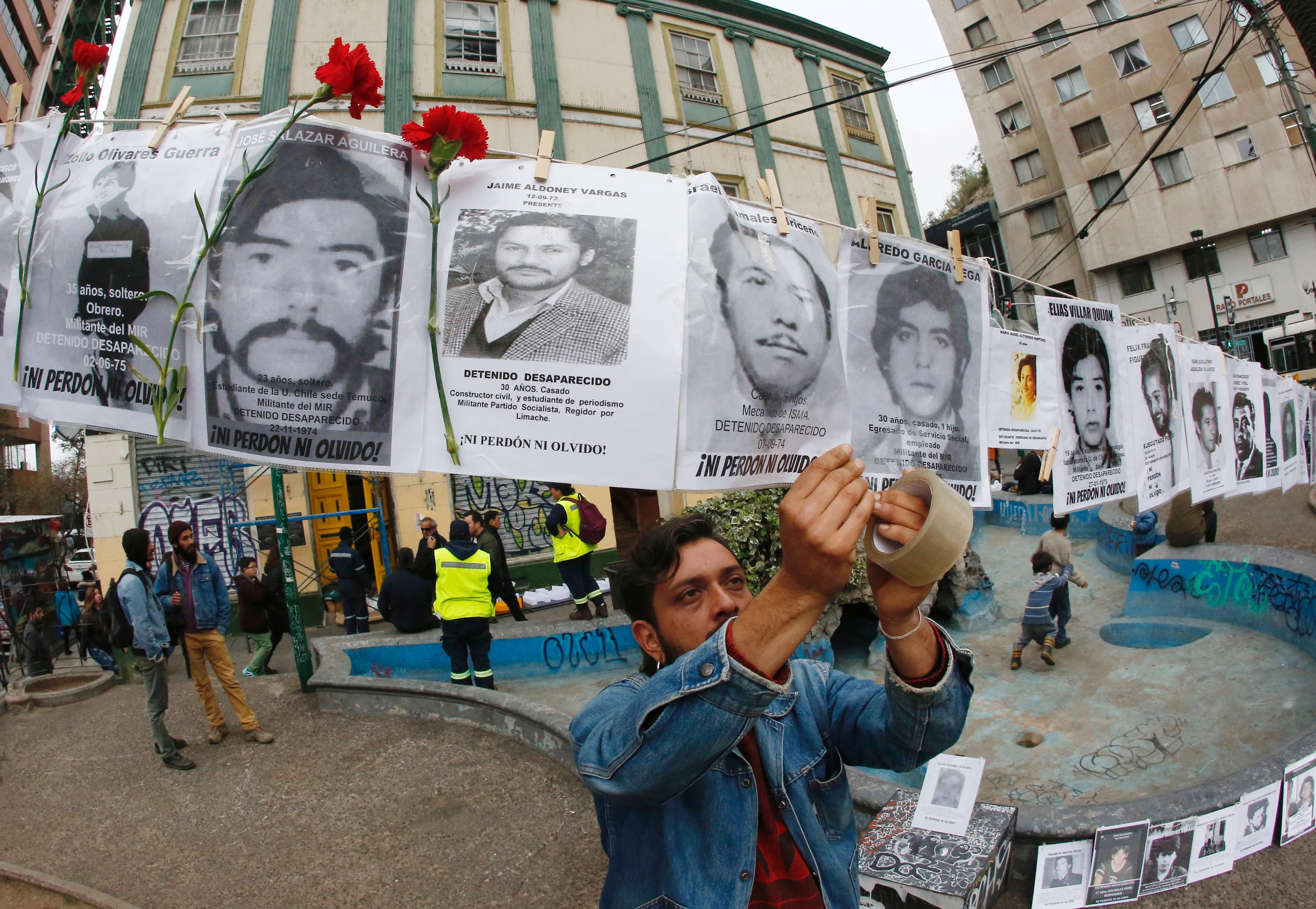 An activist hangs images of people who were forcibly disappeared during Chile's military dictatorship