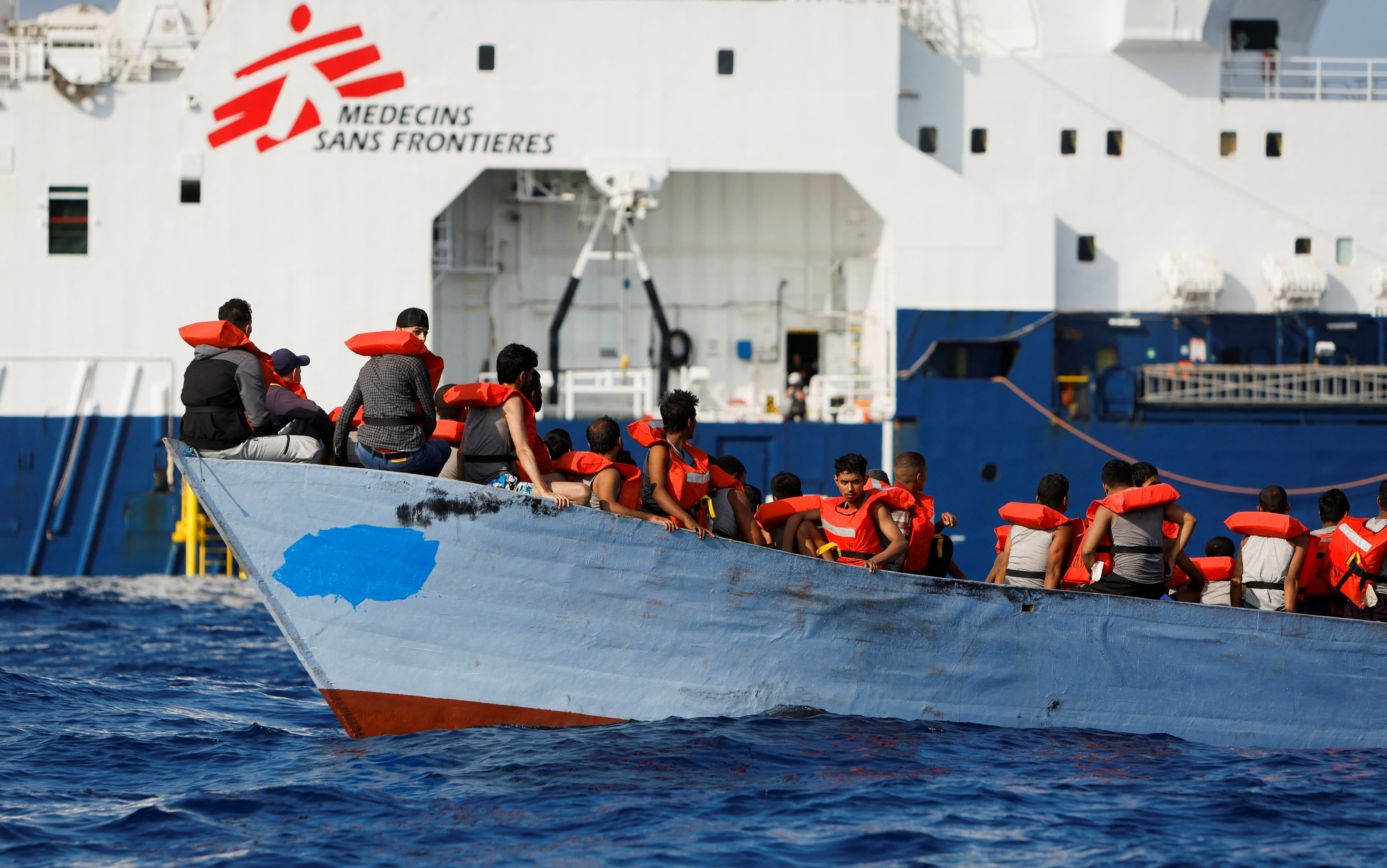 A group of 61 migrants on a wooden boat are rescued by crew members of the Geo Barents migrant rescue ship, operated by Medecins Sans Frontieres (Doctors Without Borders), in international waters off the coast of Libya in the central Mediterranean Sea