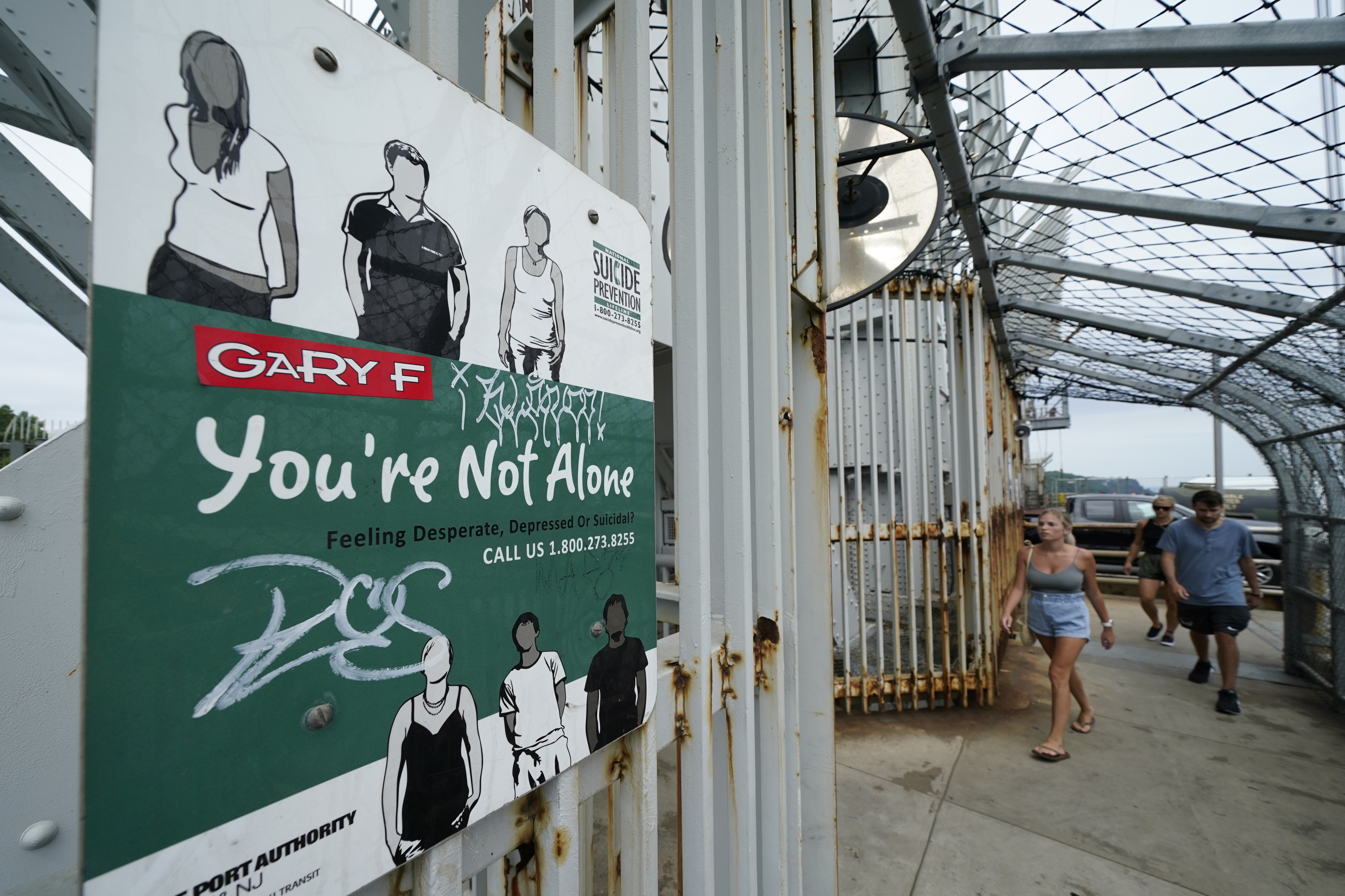 A sign for a suicide prevention hotline is displayed on the pedestrian walkway of the George Washington Bridge in New York, Monday, Aug. 9, 2021. (AP Photo/Seth Wenig)