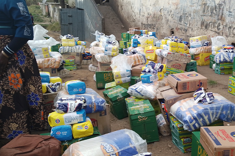 A photo of a pile of bags and boxes of rice and grains and other various essential items.