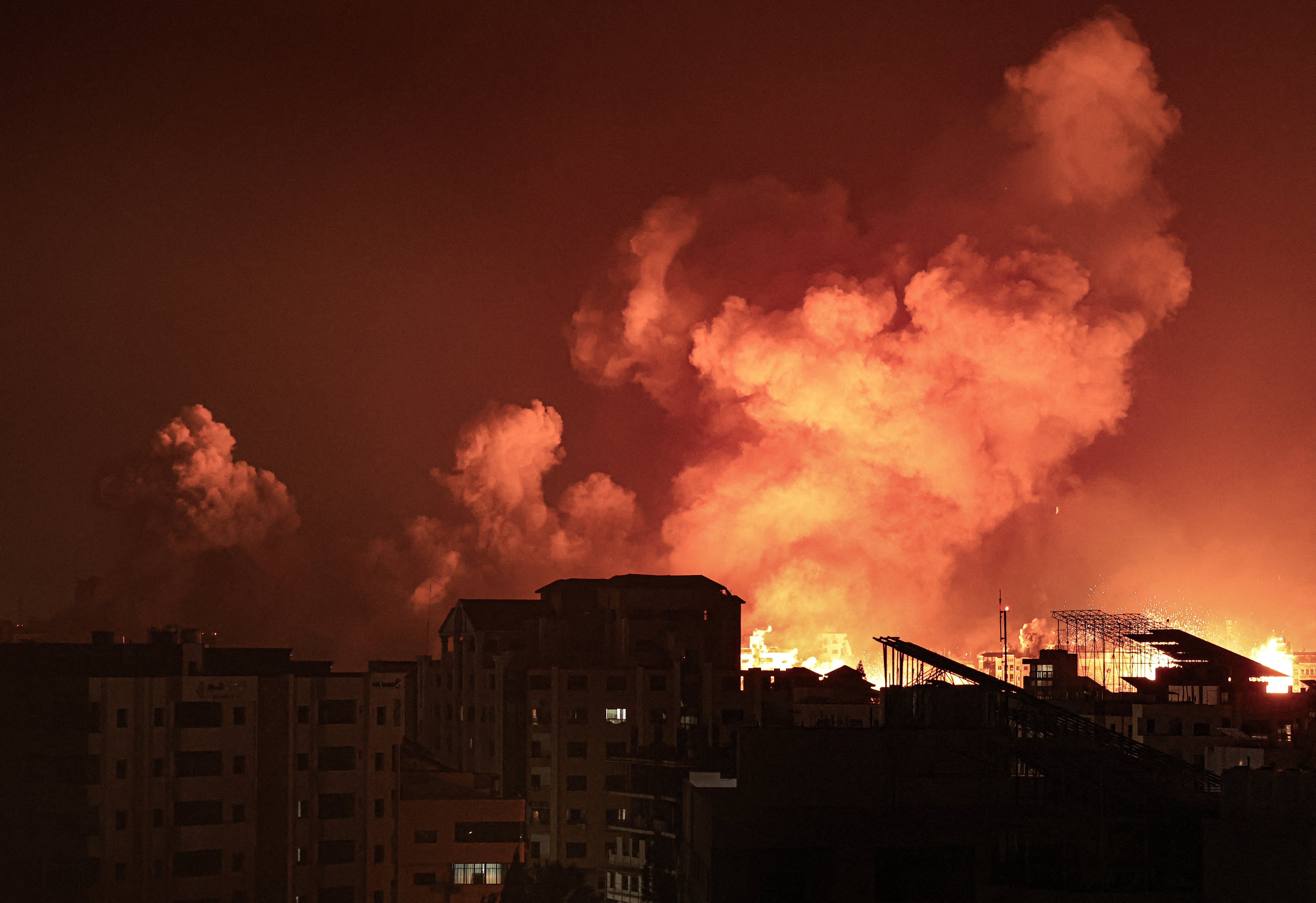 A fireball erupts during Israeli bombardment of Gaza City on October 9, 2023. Israel imposed a total siege on the Gaza Strip on October 9 and cut off the water supply as it kept bombing targets in the crowded Palestinian enclave in response to the Hamas surprise assault it has likened to the 9/11 attacks. (Photo by MAHMUD HAMS / AFP)