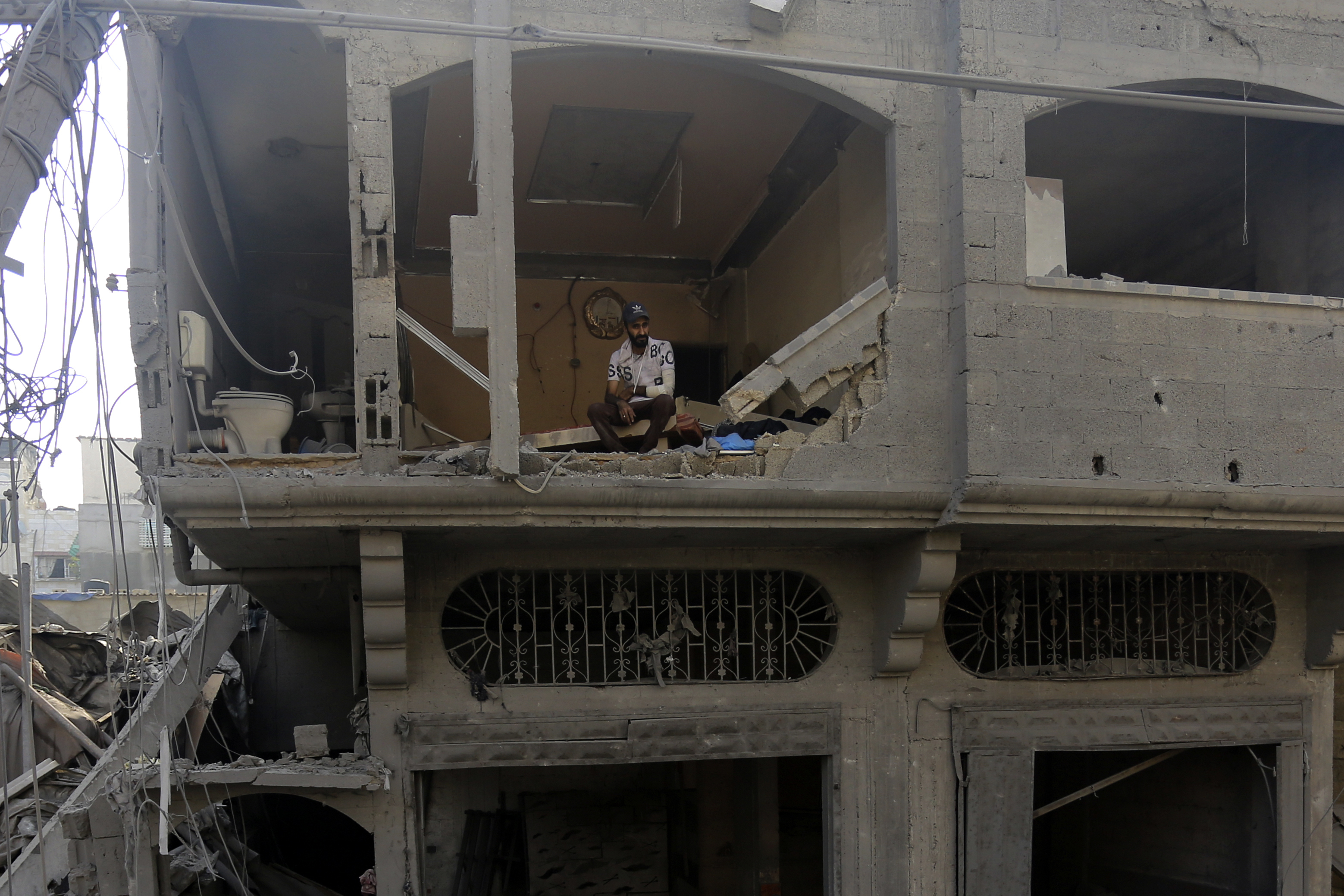 A Palestinian man watches as others inspect the damage to destroyed houses after Israeli airstrikes on Gaza City