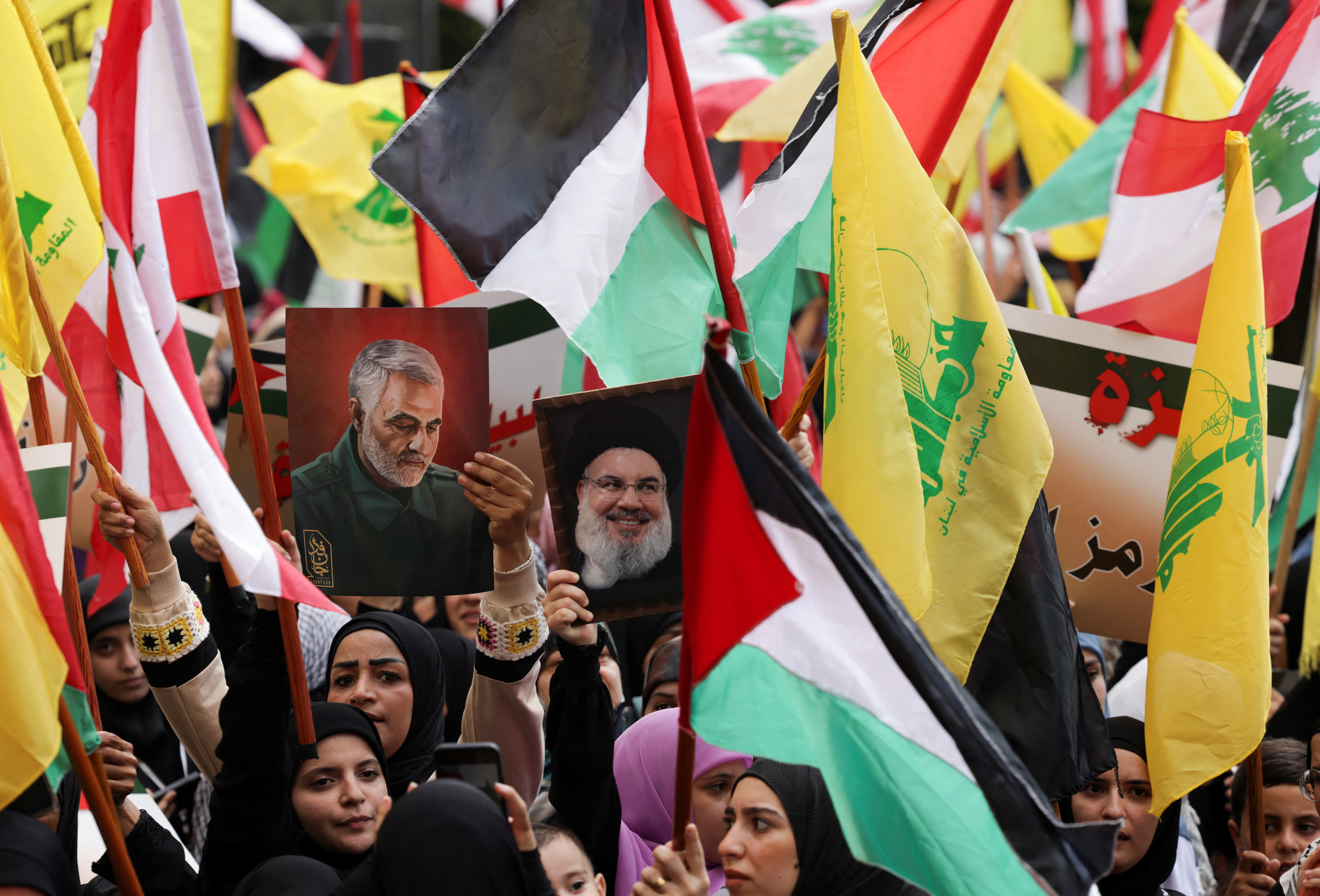 Hezbollah supporters carry flags and placards with pictures of Hezbollah leader Sayyed Hassan Nasrallah and late Iranian Quds Force Major-General Qassem Soleimani, as they attend a rally supporting Palestinians in Gaza, amid the ongoing conflict between Israel and the Palestinian Islamist group Hamas, in Beirut, Lebanon October 13, 2023.