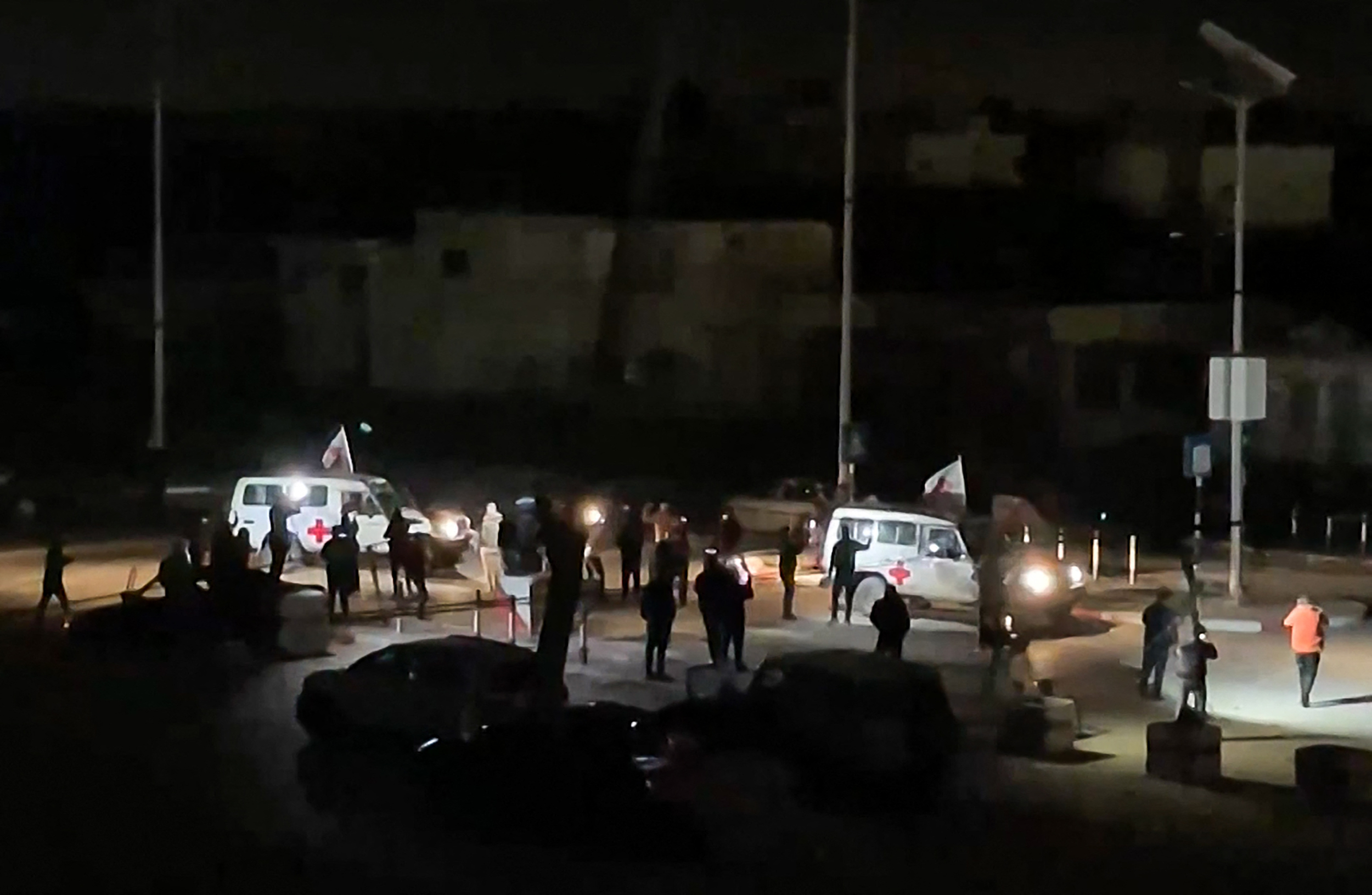 two white vehicles with red crosses on the door against a dark sky