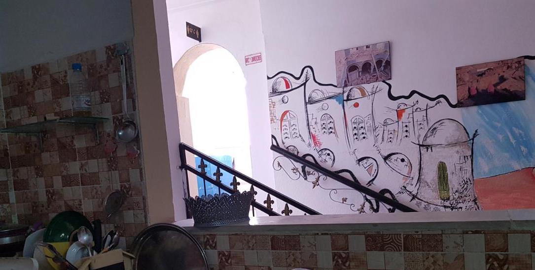 A photo of a wall by some stairs with a illustrations of buildings.