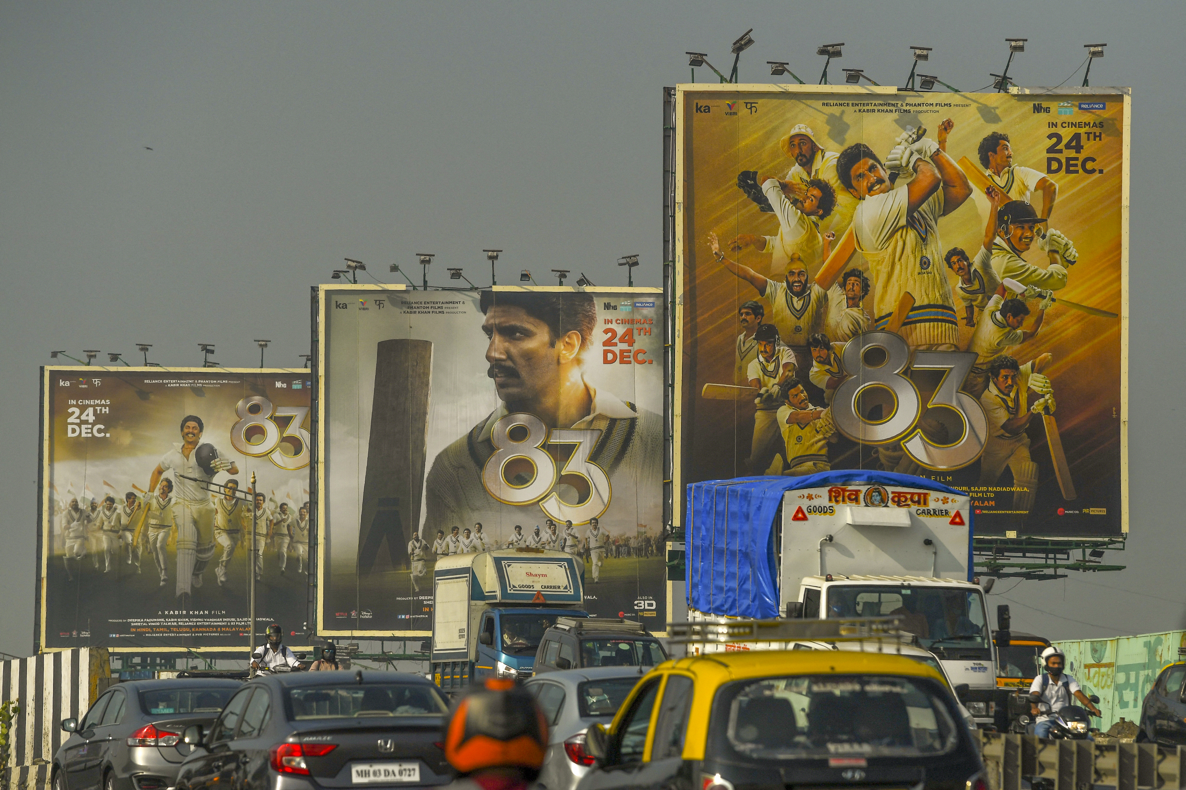 Vehicles move past billboards of Bollywood film '83'