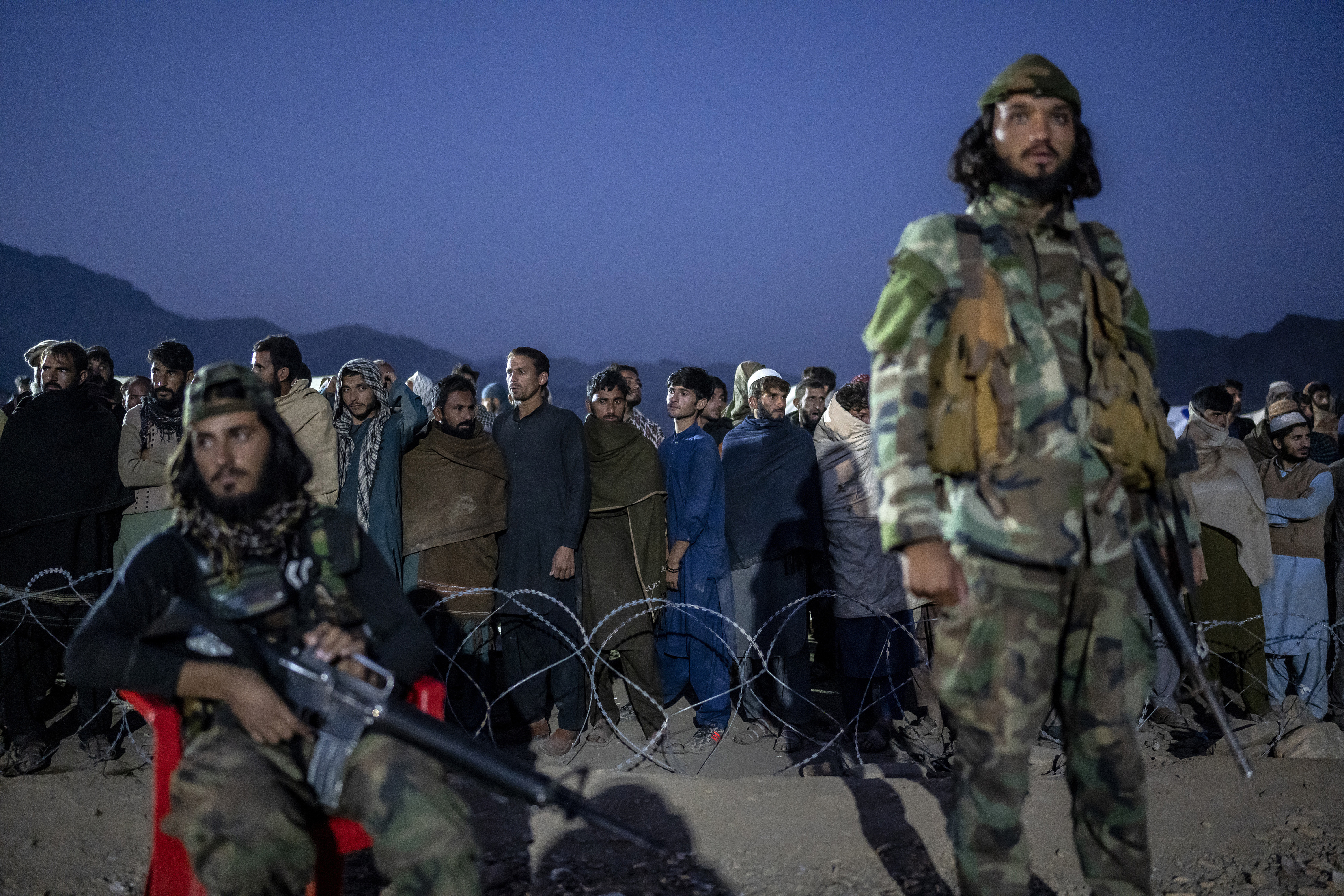 Taliban fighters stand guard as Afghan refugees line up to register in a camp near the Torkham Pakistan-Afghanistan border in Torkham, Afghanistan.