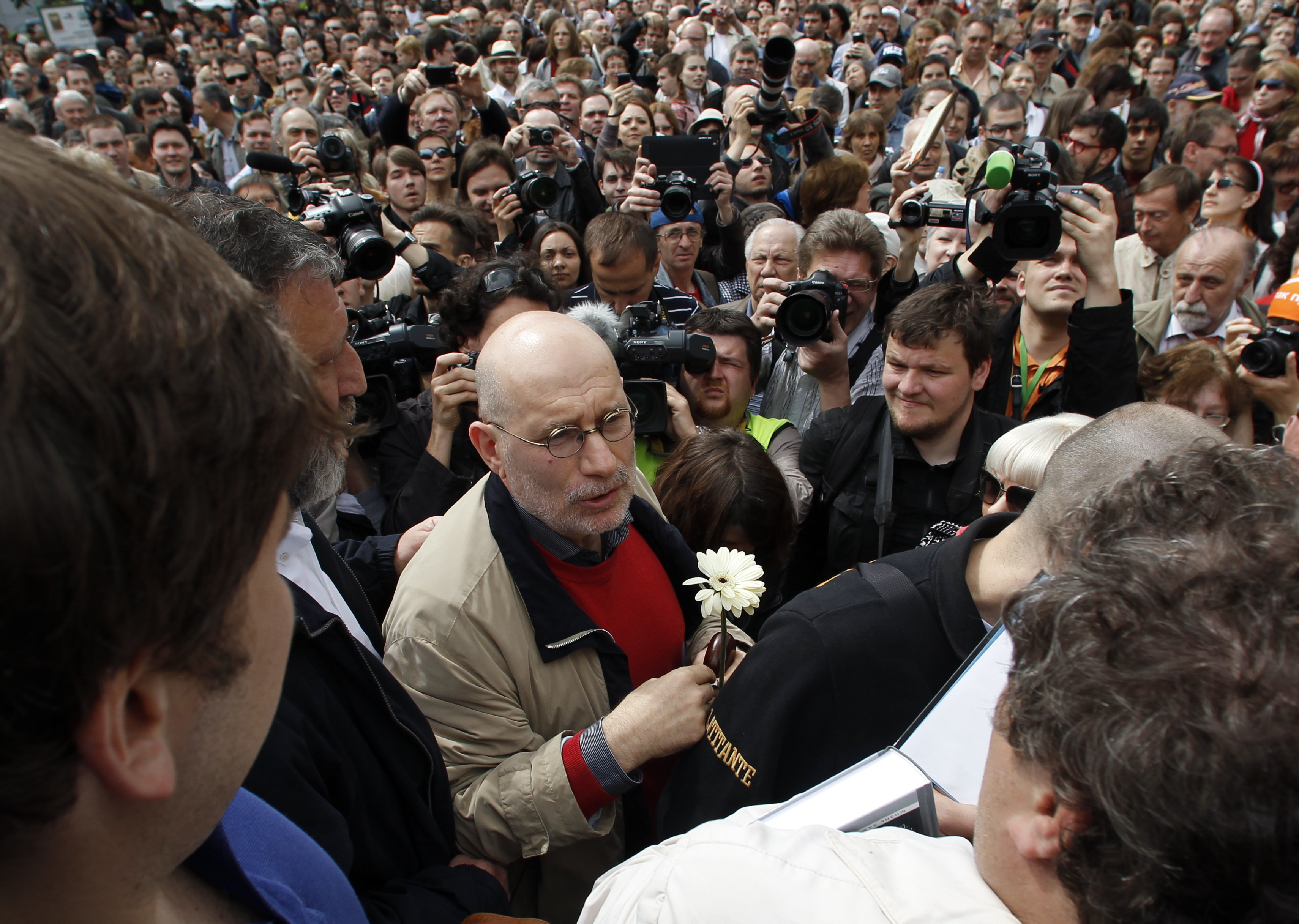 Boris Akunin, wearing a white flower, marches with a crowd in Moscow