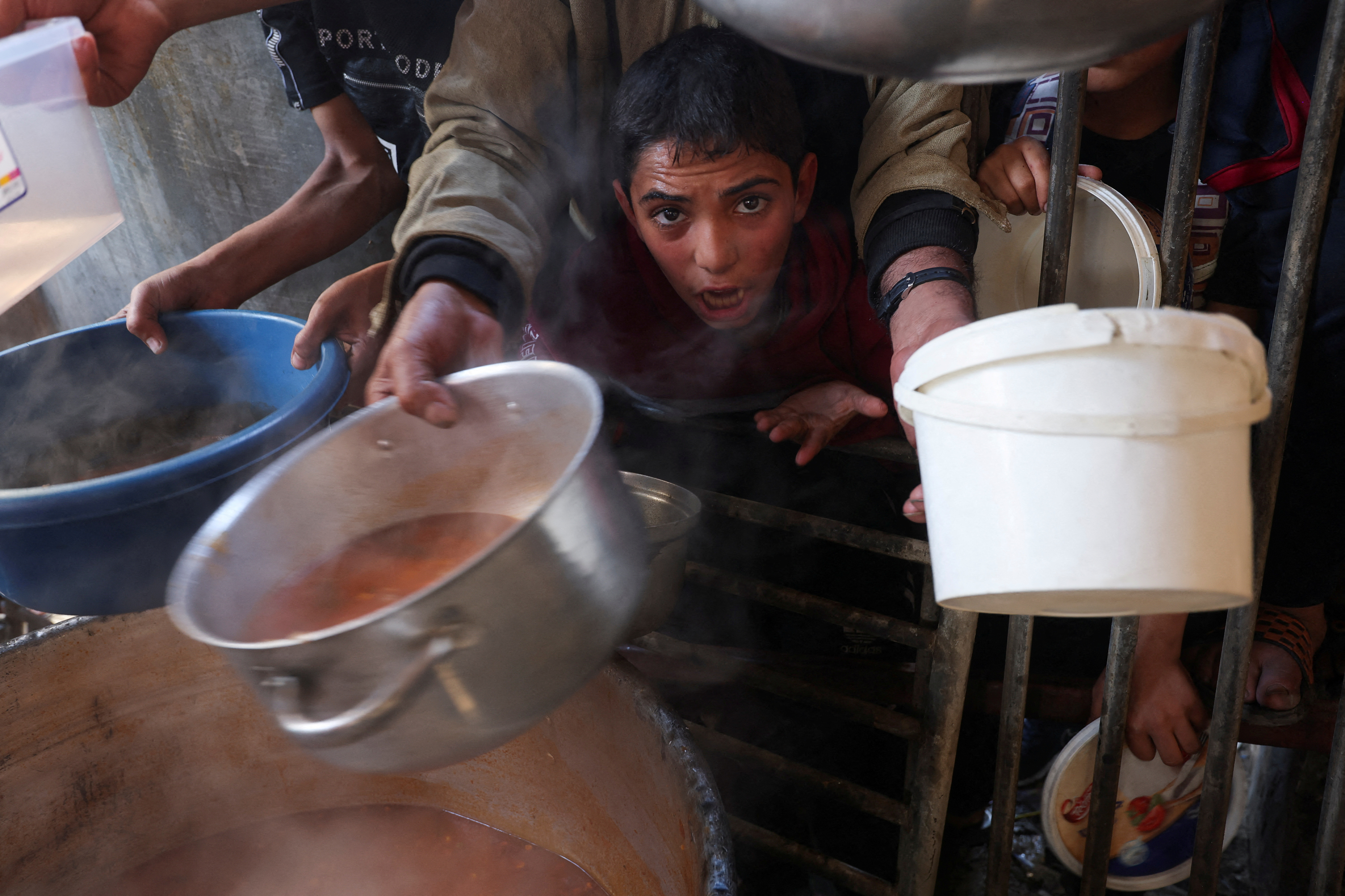 A Palestinian child reacts, while people gather to get their share of charity food offered by volunteers, amid food shortages, as the conflict between Israel and the Palestinian Islamist group Hamas continues, in Rafah, in the southern Gaza Strip, December 2, 2023. REUTERS/Ibraheem Abu Mustafa TPX IMAGES OF THE DAY