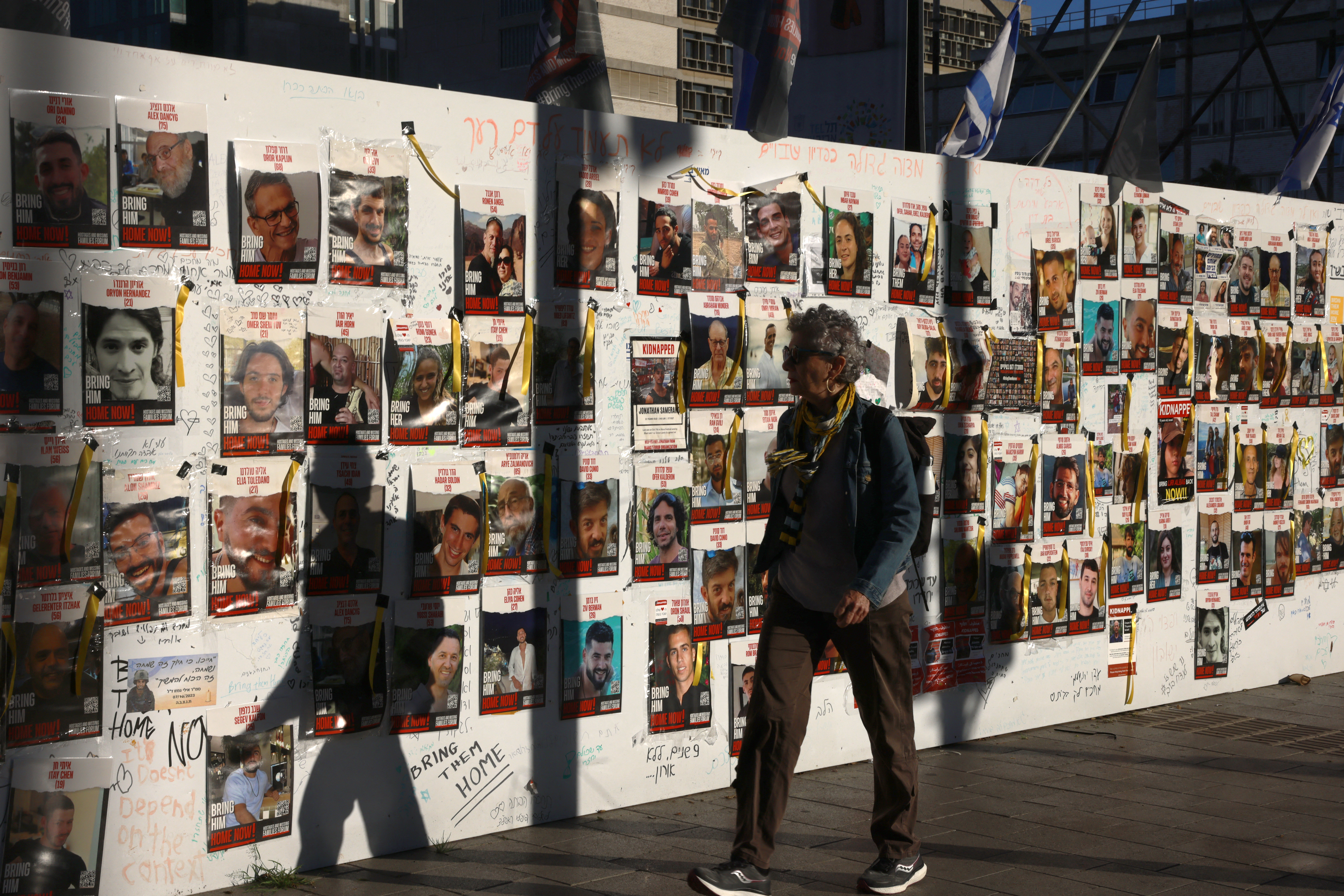 People pass by portraits of Israeli hostages held in Gaza since the October 7 attacks by Palestinian Hamas militants, posted on a wall in Tel Aviv.