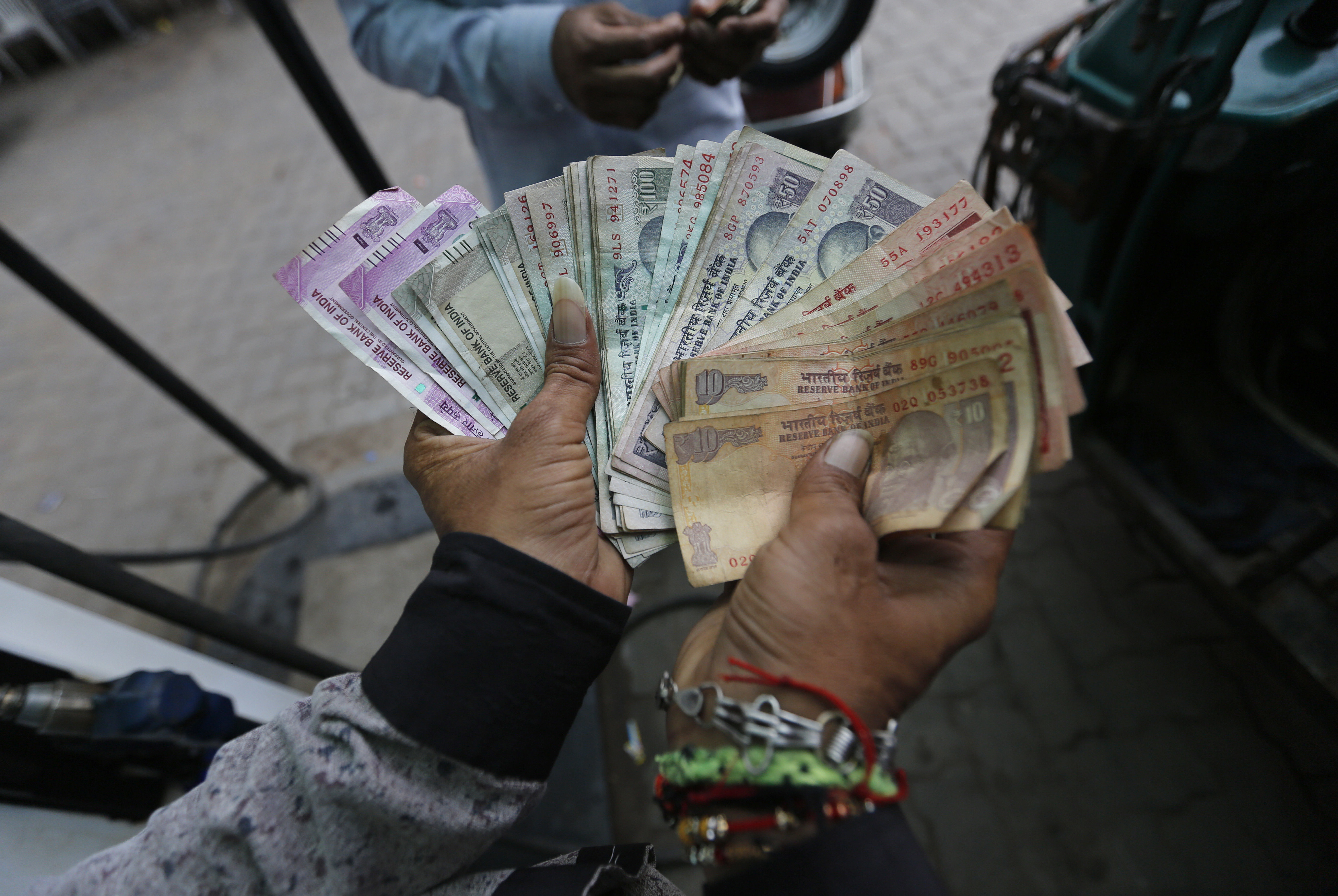 An employee of a fuel station counts Indian currency notes to give change to a customer after filling fuel in Ahmadabad
