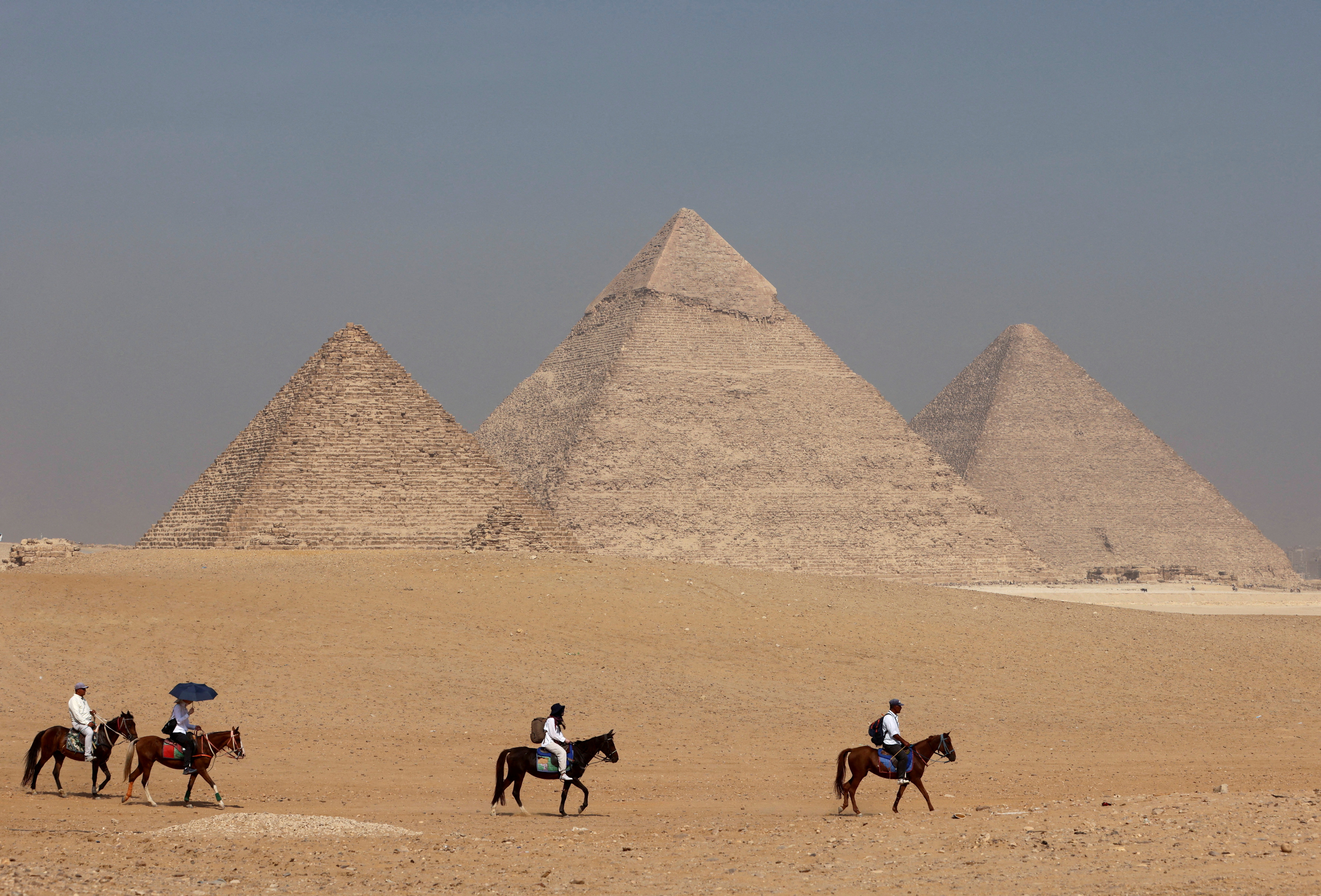 Tourists ride horses in front of the Great Pyramid of Giza, on the outskirts of Cairo, Egypt, October 26, 2023. REUTERS/Mohamed Abd El Ghany REFILE - CORRECTING YEAR FROM "2022" TO "2023
